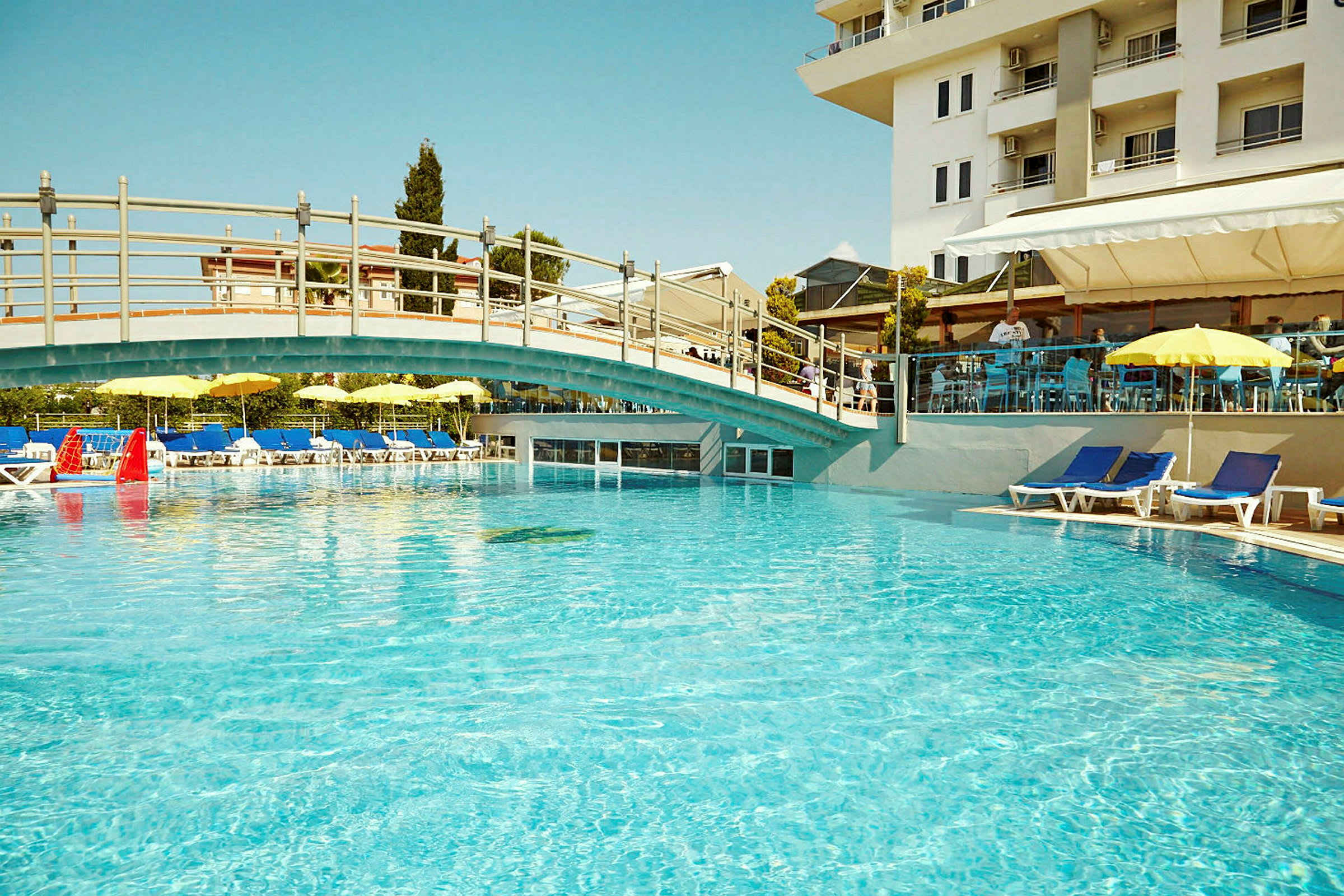 En utomhuspool med solstolar och parasoller vid ett hotell. (AI-genererad text)