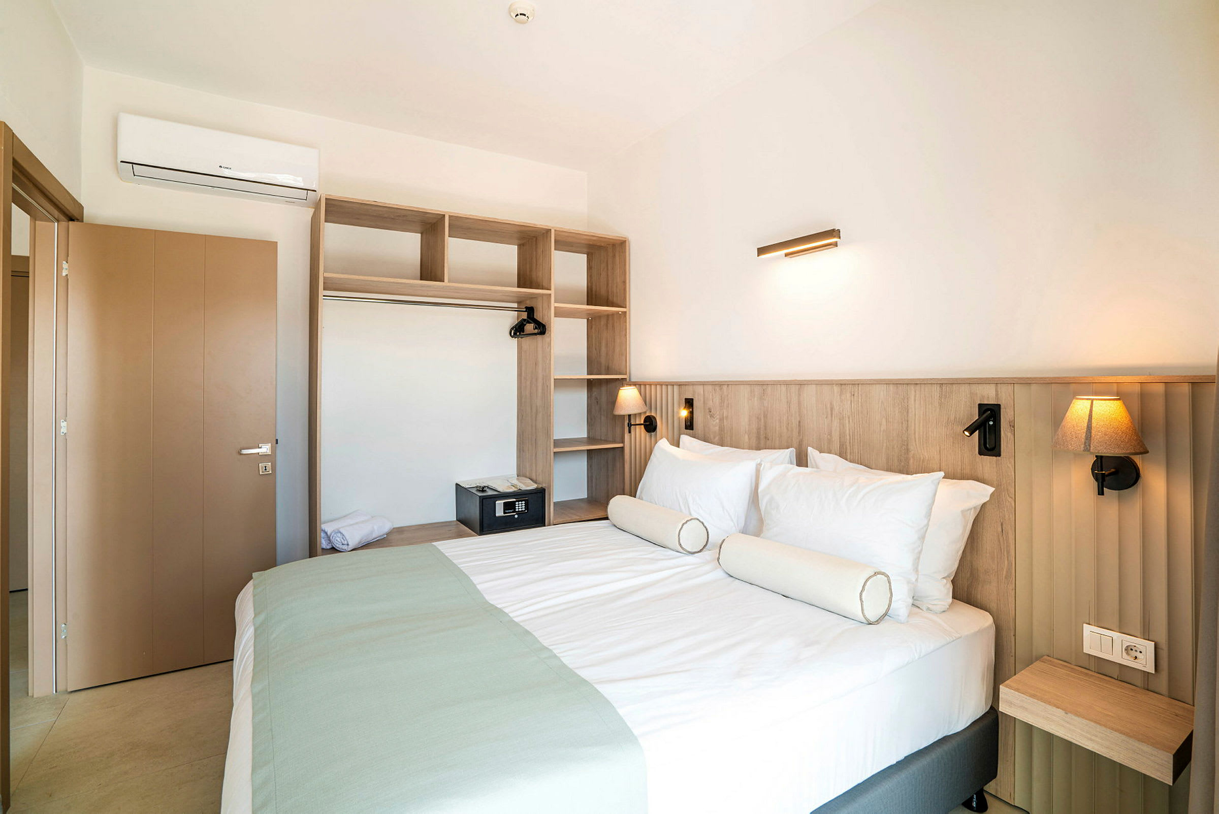 Hotellrum med dubbelsäng och öppet garderobssystem. (AI-genererad text)