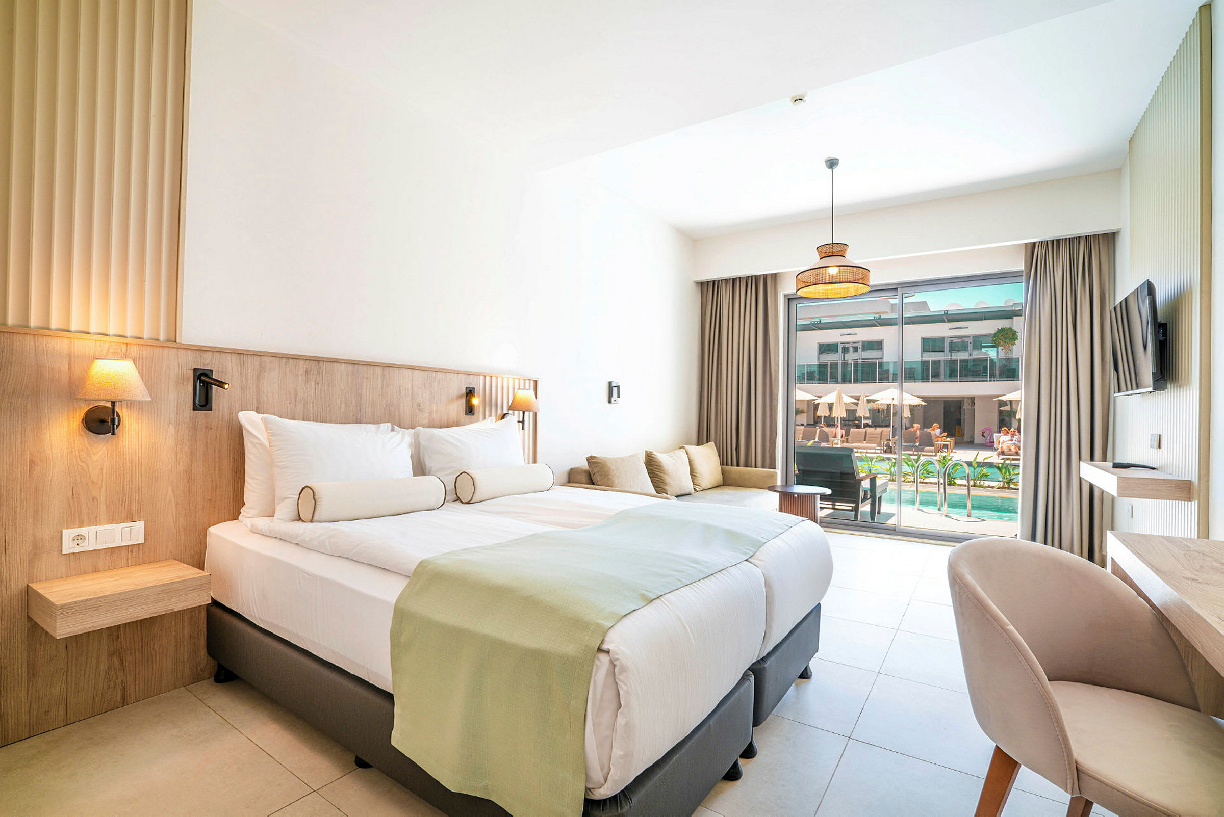 Hotellrum med dubbelsäng, soffa och utsikt mot en pool. (AI-genererad text)