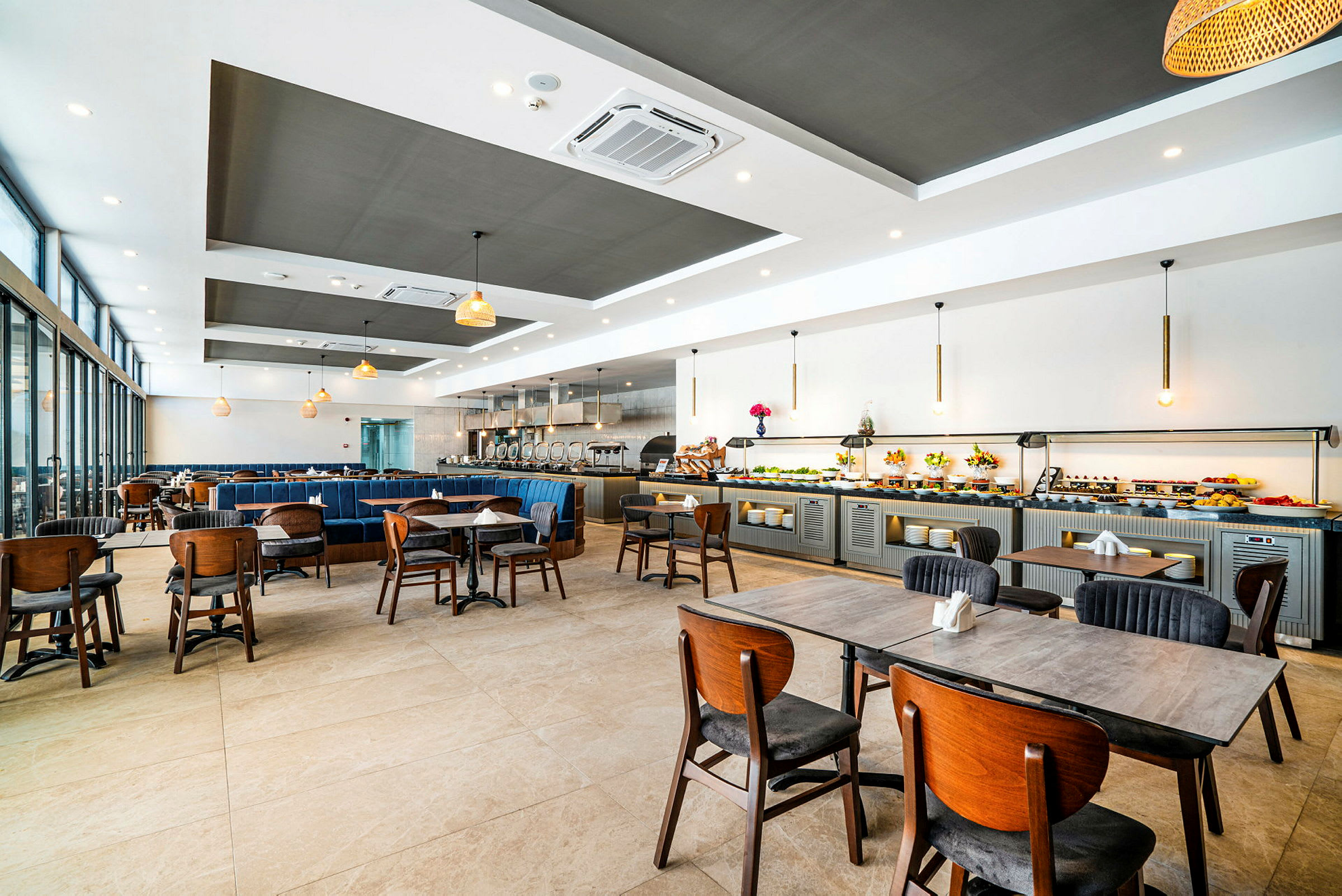 En rymlig restaurang med bord och stolar, samt en buffédisk längs väggen. (AI-genererad text)