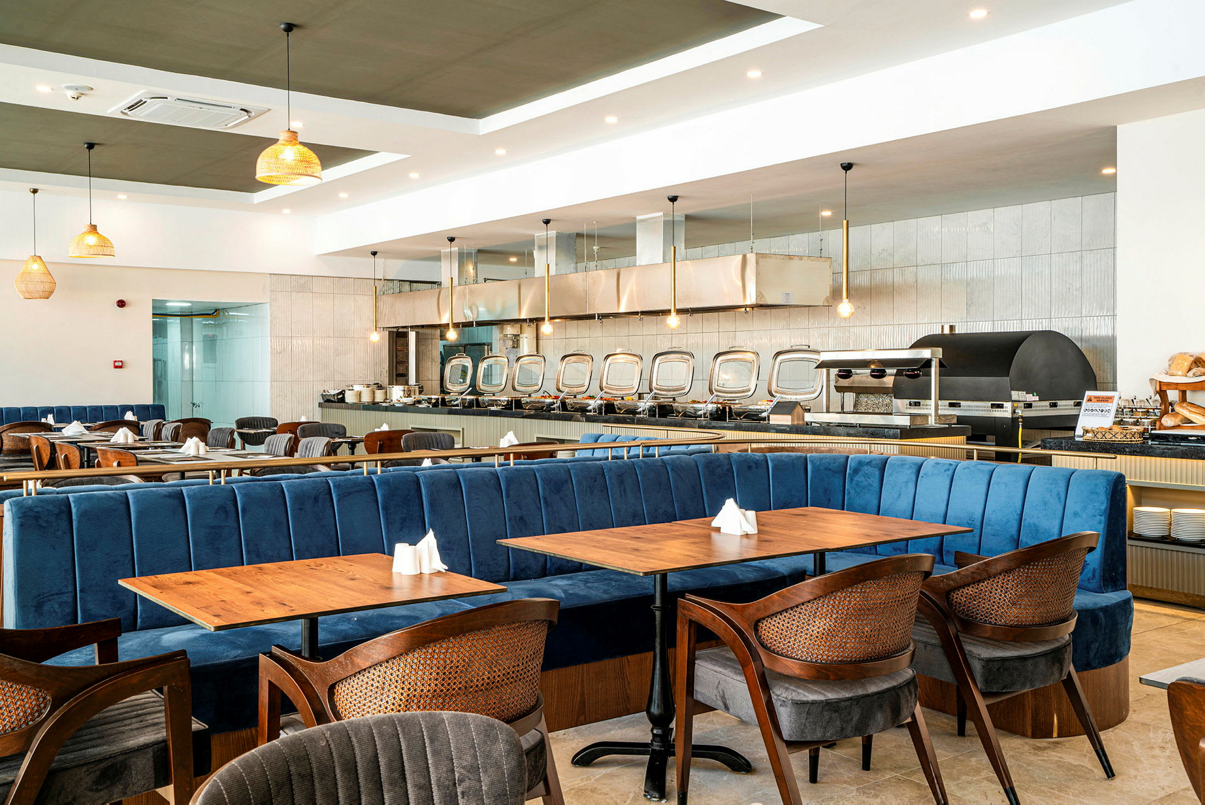 Interiör av en restaurang med blå soffor, träbord och belysning. (AI-genererad text)