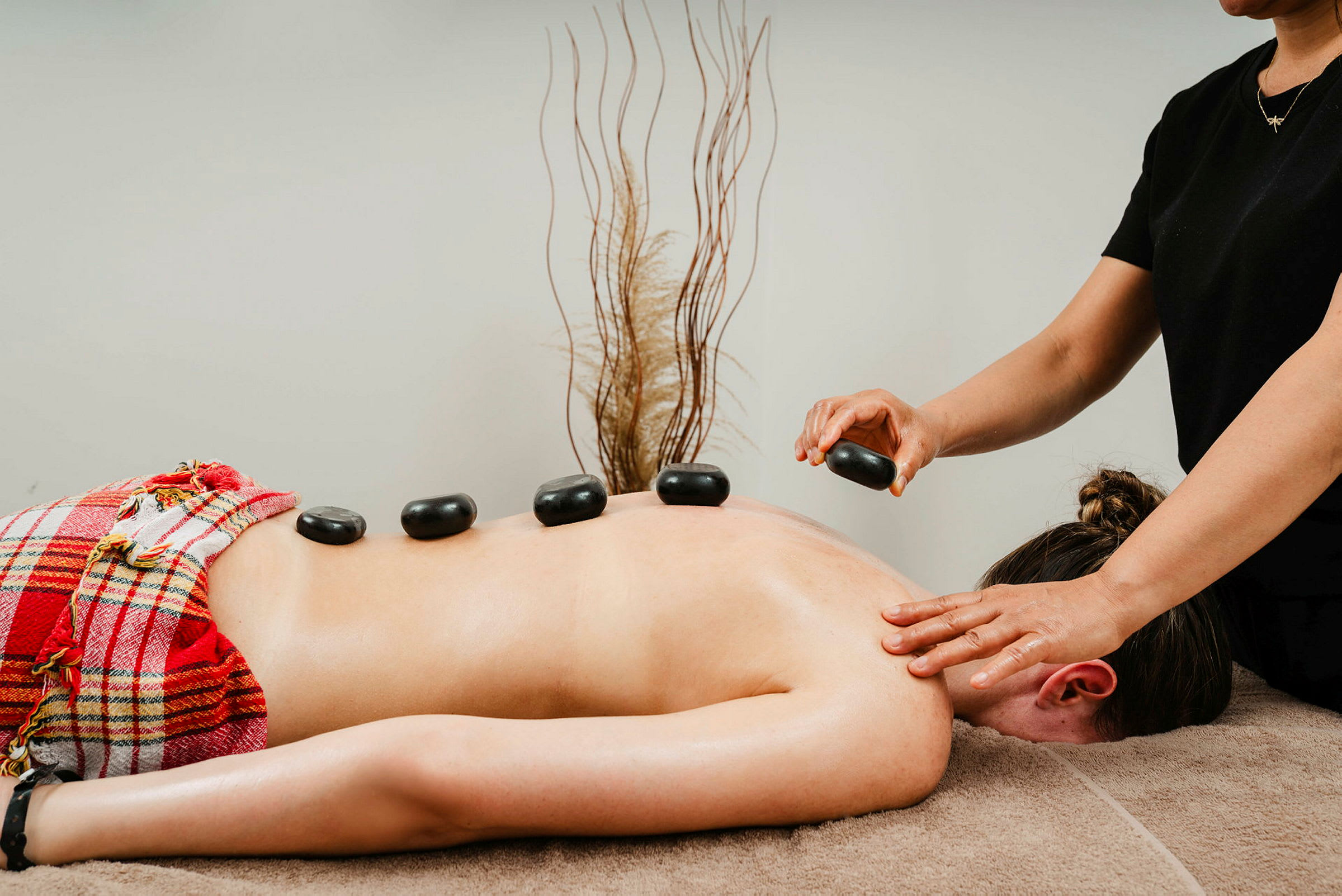 En person får hot stone-massage med stenar placerade på ryggen. (AI-genererad text)