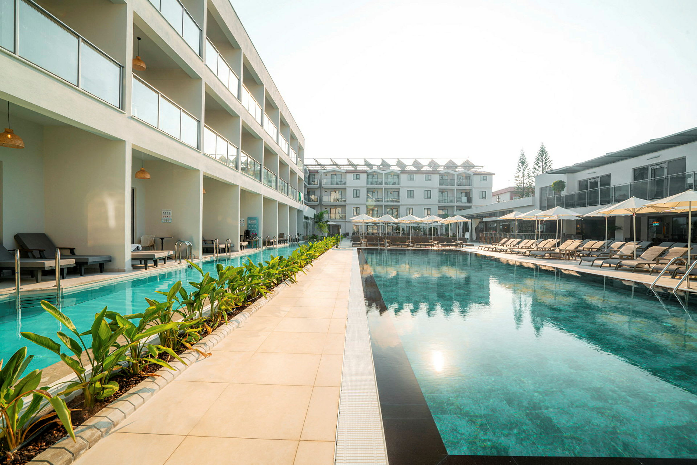 Utomhuspool vid hotellområde med solstolar och moderna byggnader. (AI-genererad text)