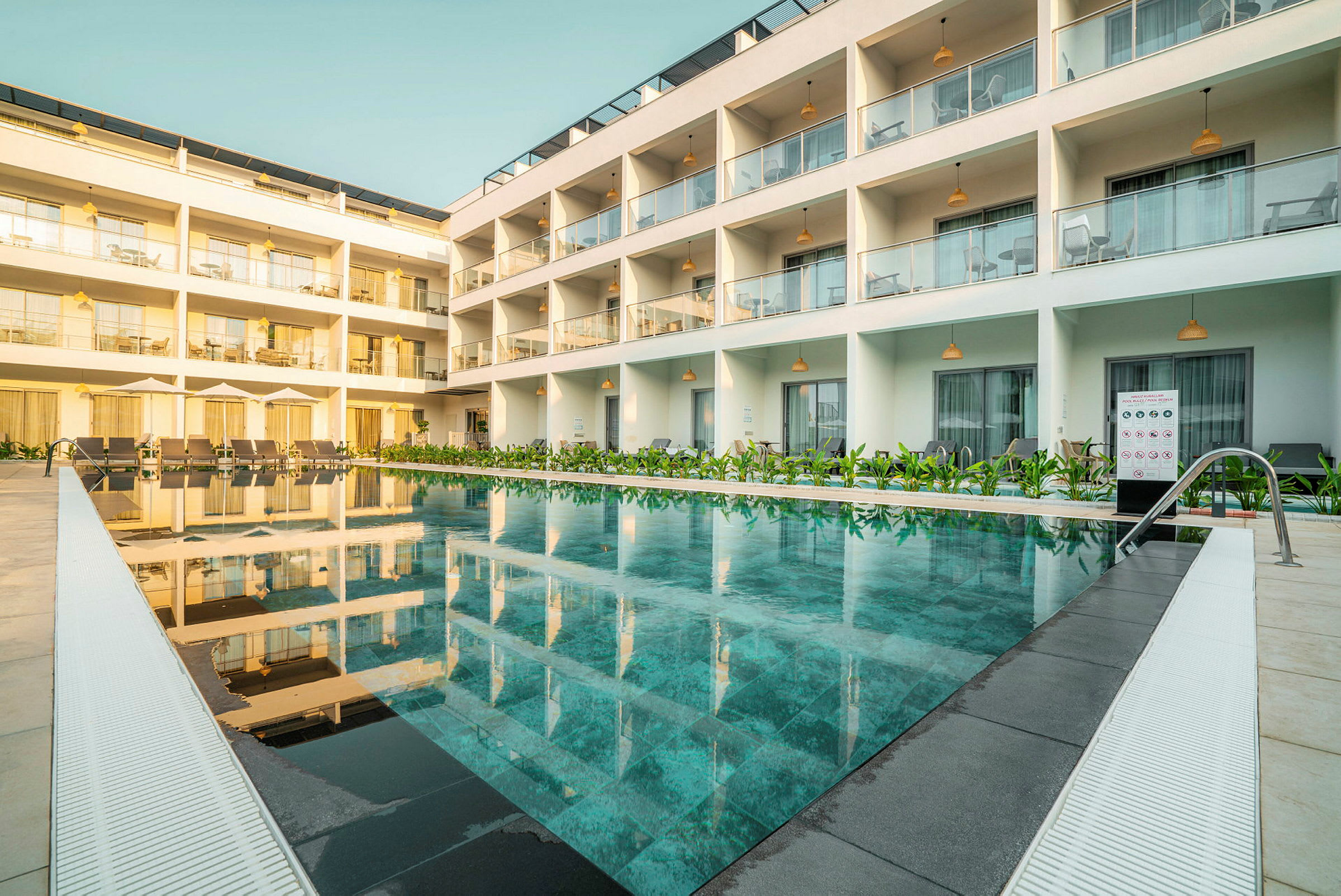 Modern byggnad med pool och solstolar framför. (AI-genererad text)