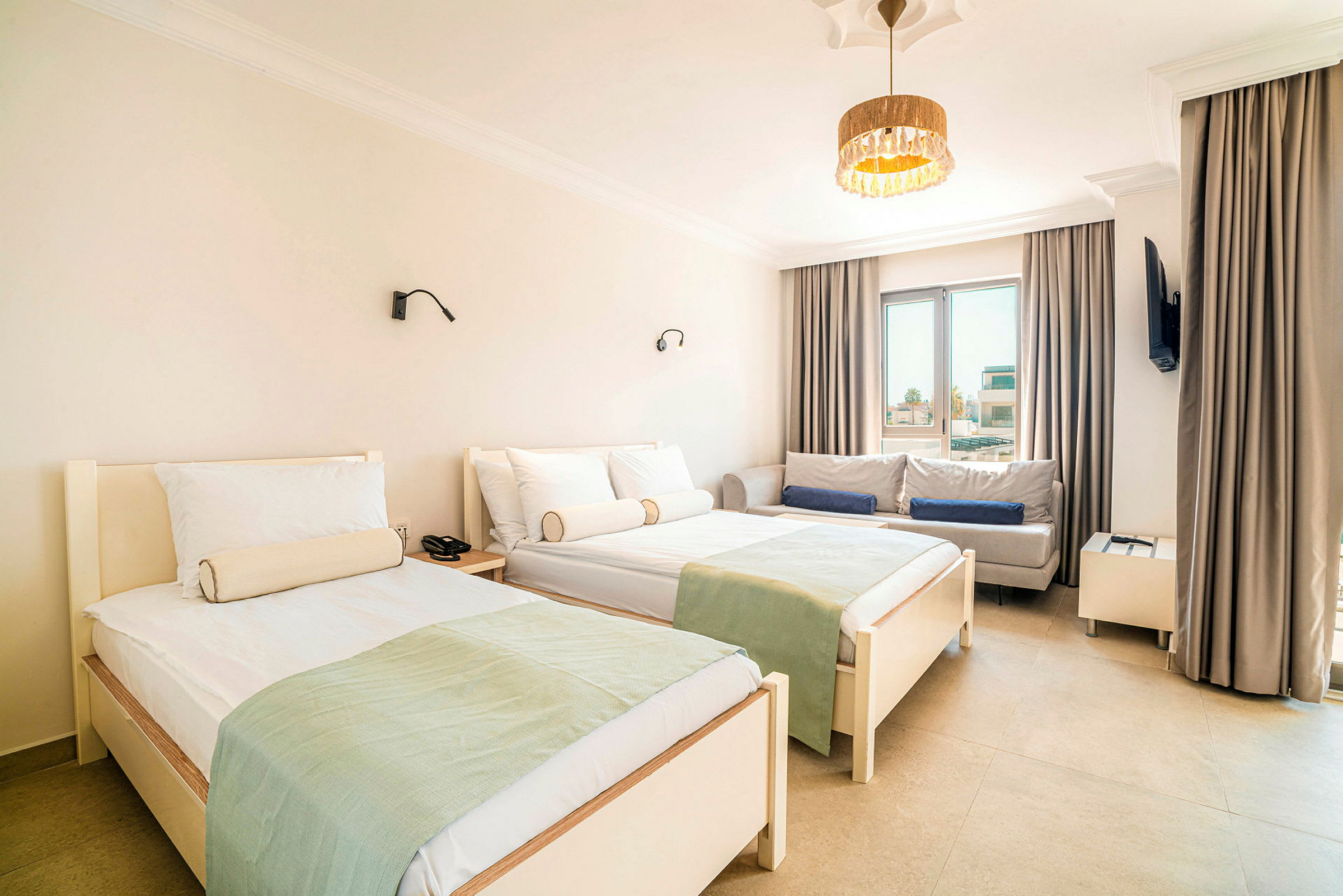 Ett hotellrum med två enkelsängar, en soffa och ett fönster. (AI-genererad text)