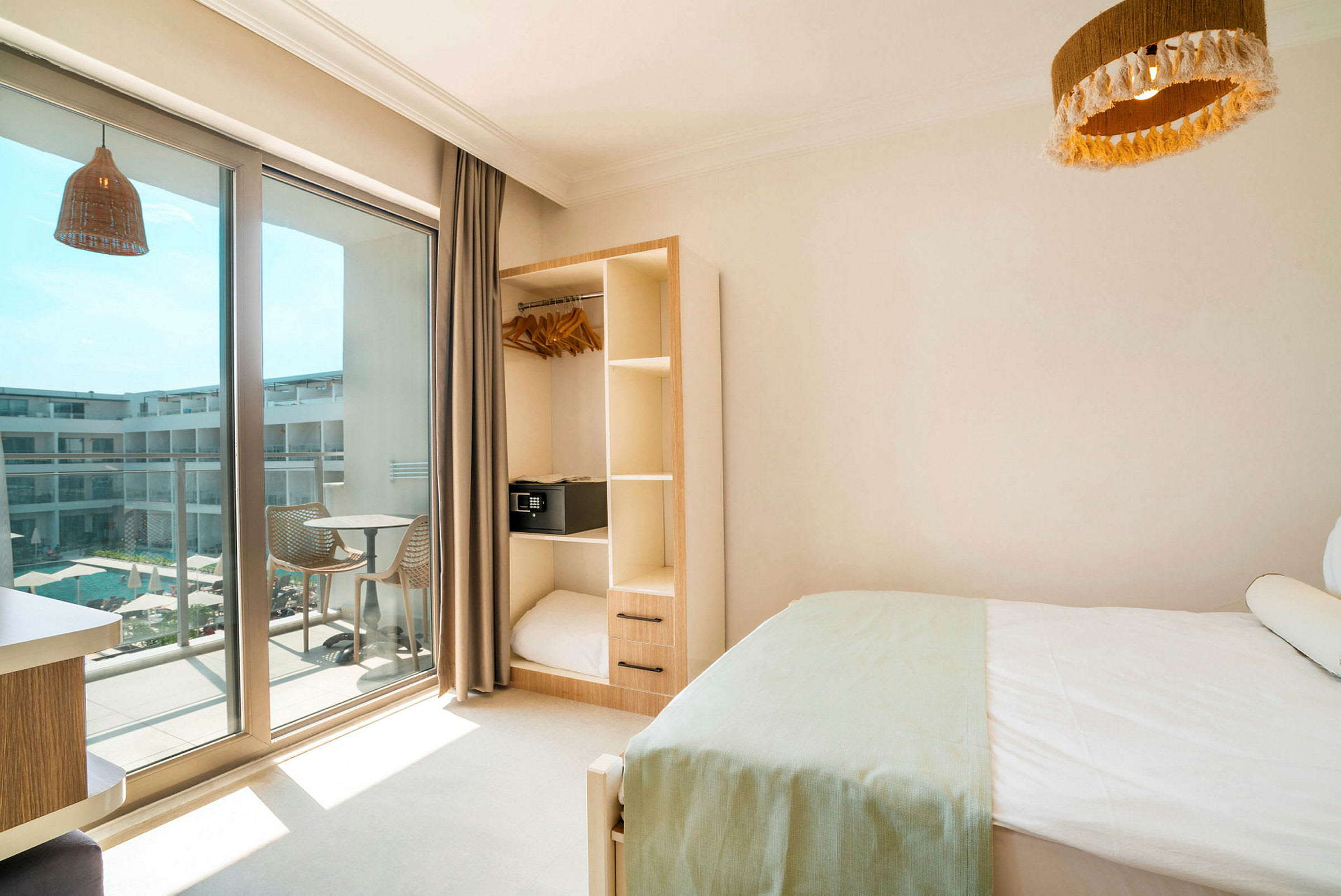 Hotellrum med säng, garderob och balkong som vetter mot en pool. (AI-genererad text)