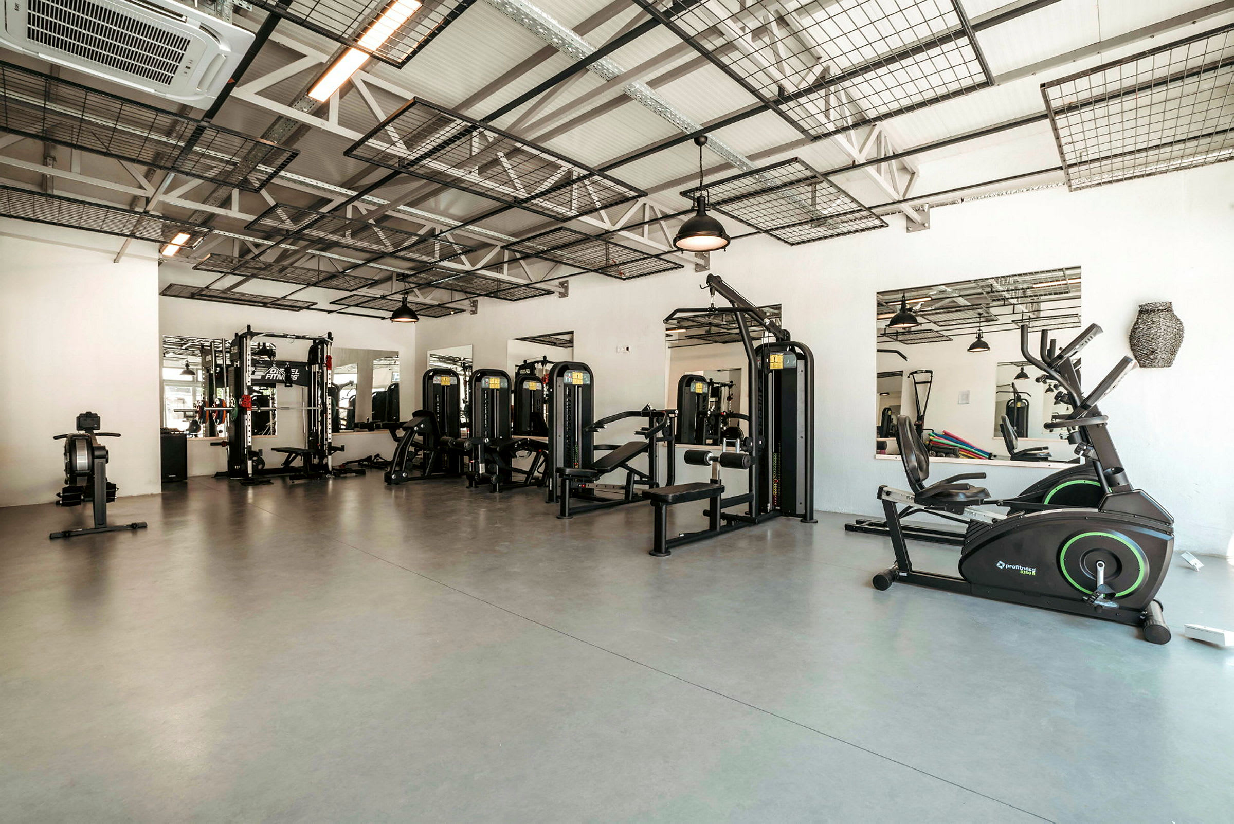 Ett gym med träningsutrustning såsom styrketräningsmaskiner och motionscyklar. (AI-genererad text)