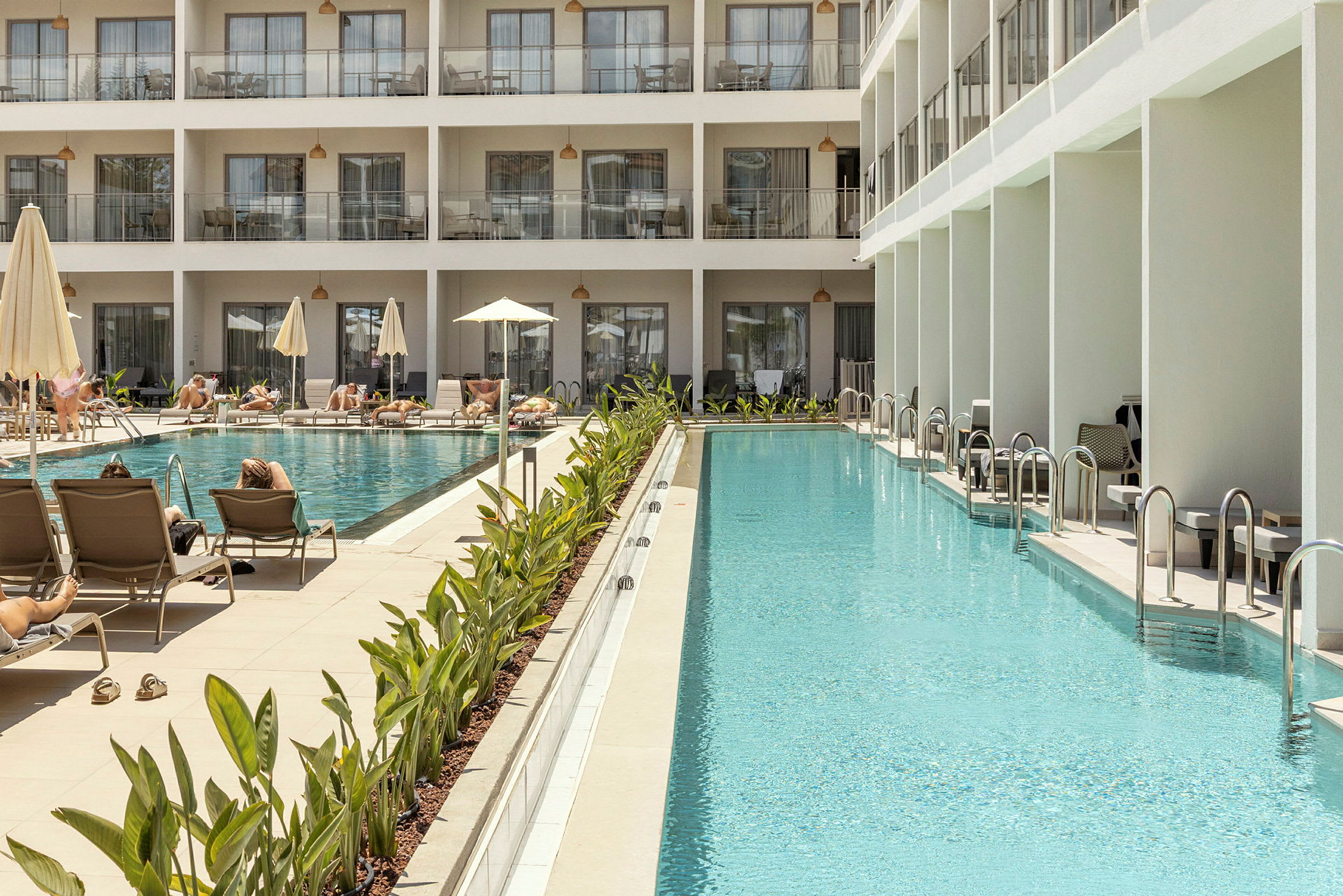 Ett lyxigt hotel med solstolar och parasoller vid en stor pool. (AI-genererad text)