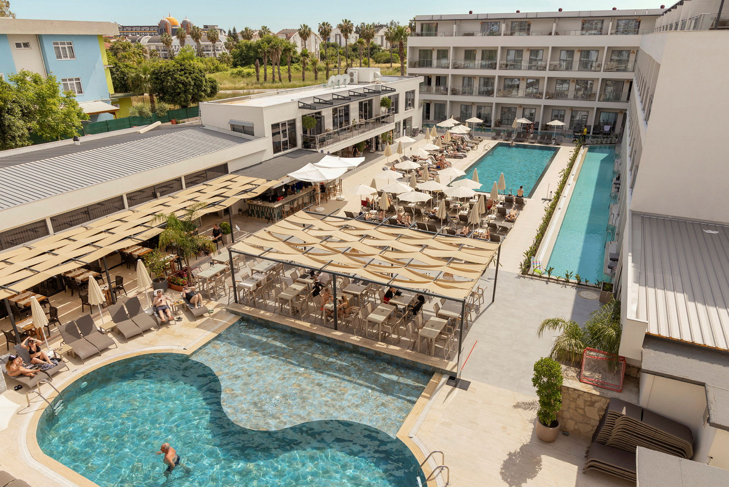 Hotellets poolområde med solstolar, parasoller och en servering vid poolen. (AI-genererad text)