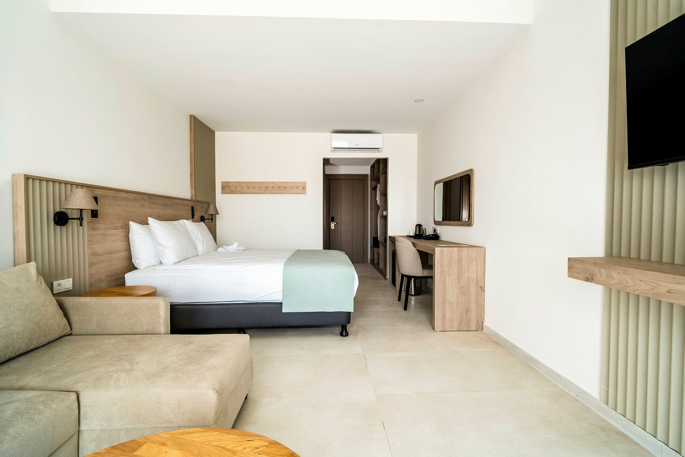 Ett hotellrum med en dubbelsäng, en soffa, ett skrivbord och en TV. (AI-genererad text)