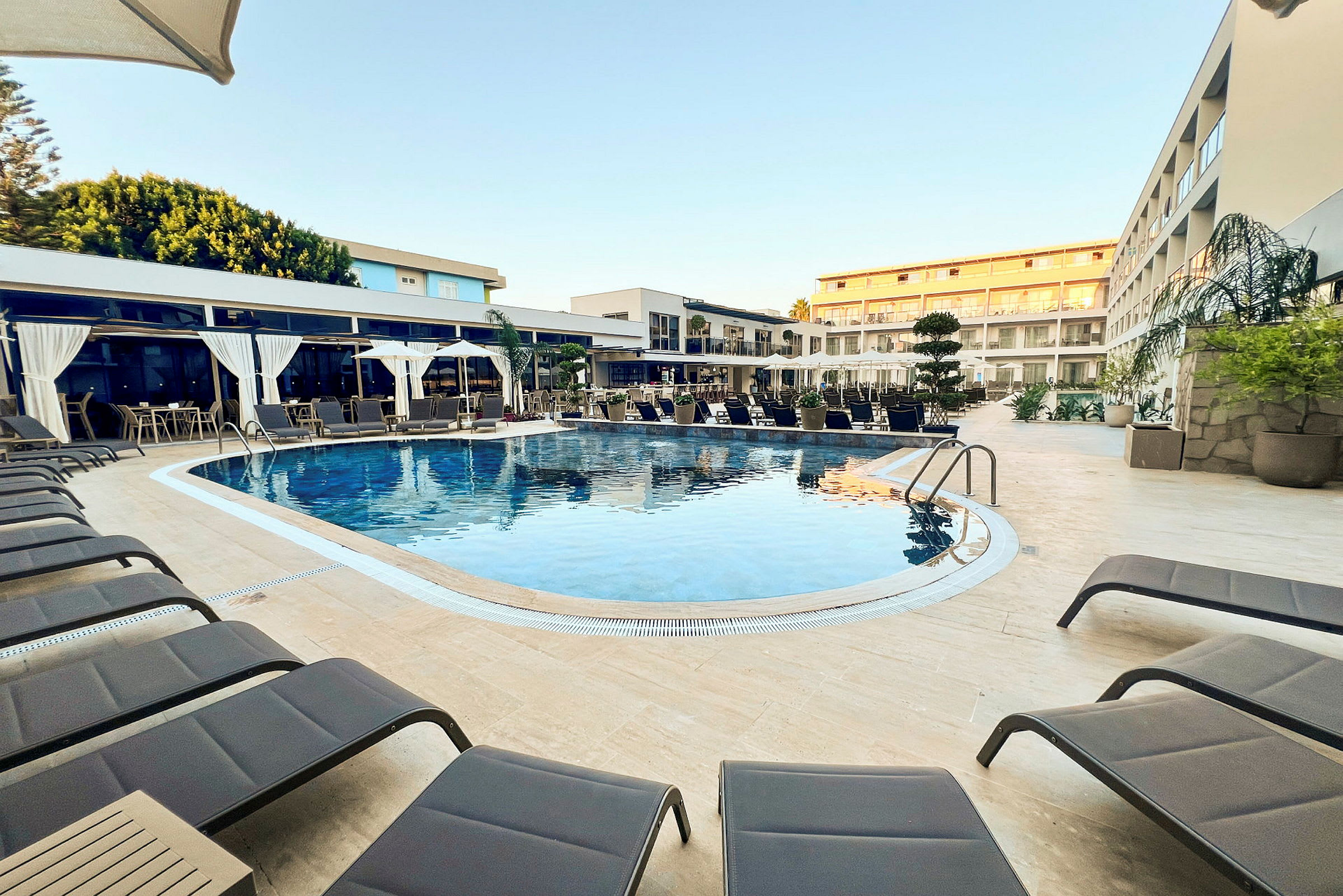 Utomhuspool med solstolar och hotellbyggnader i bakgrunden. (AI-genererad text)