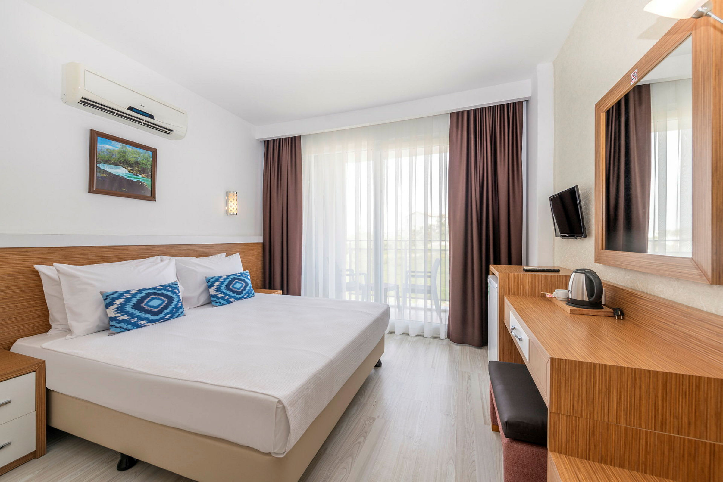 Ett hotellrum med en dubbelsäng, skrivbord och balkong. (AI-genererad text)