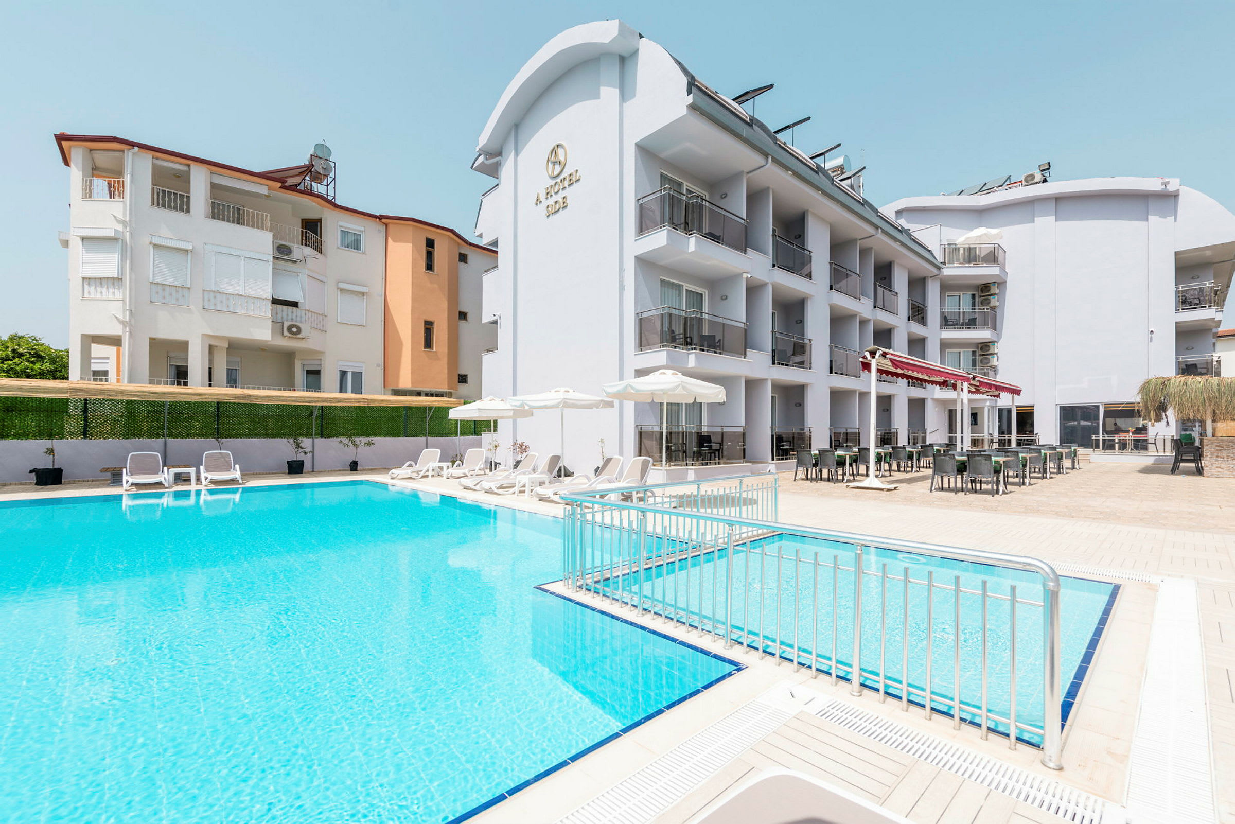 Hotell med poolområde och solstolar i förgrunden. (AI-genererad text)