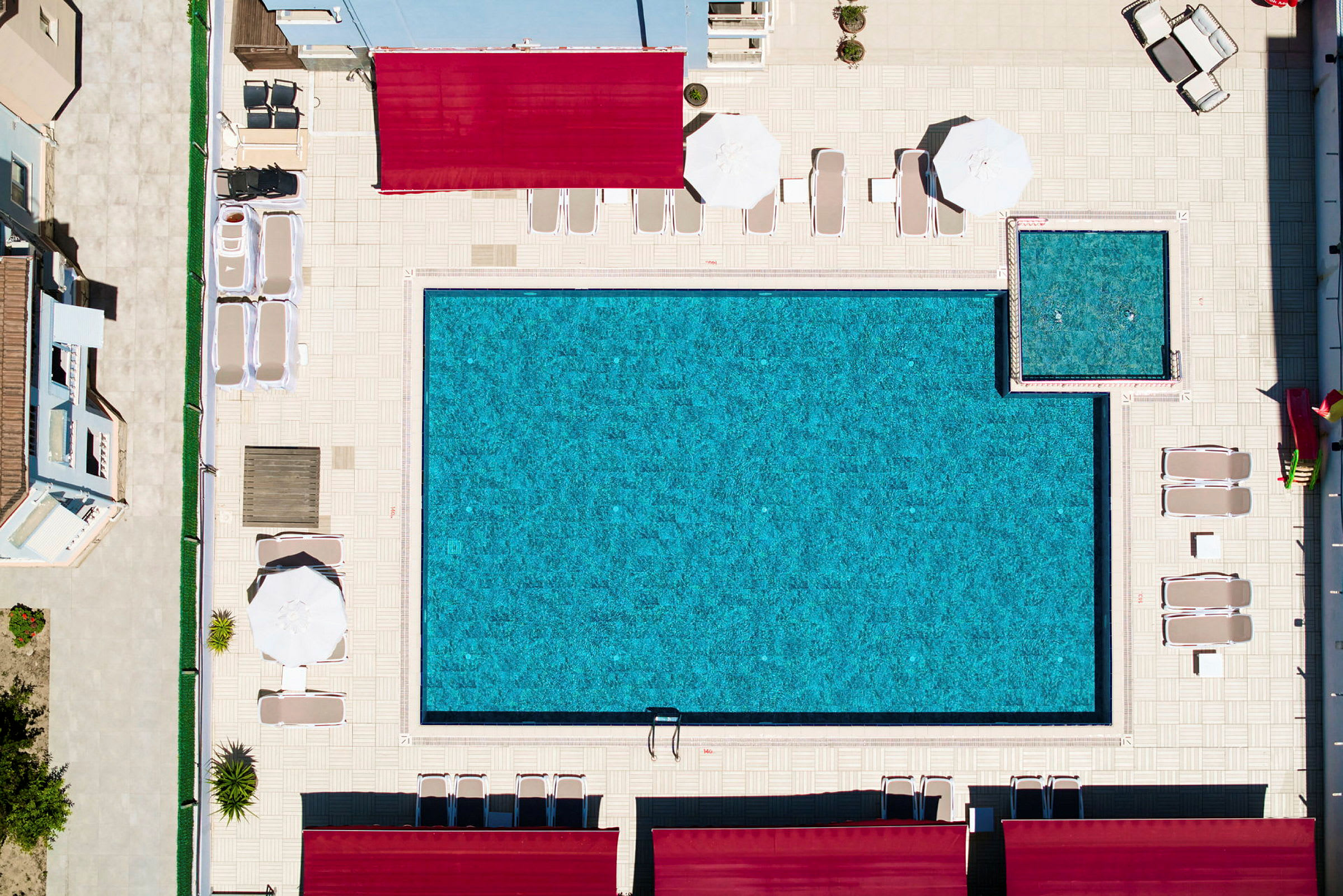 Flygfoto över en swimmingpool och solstolar på en bassängområde. (AI-genererad text)