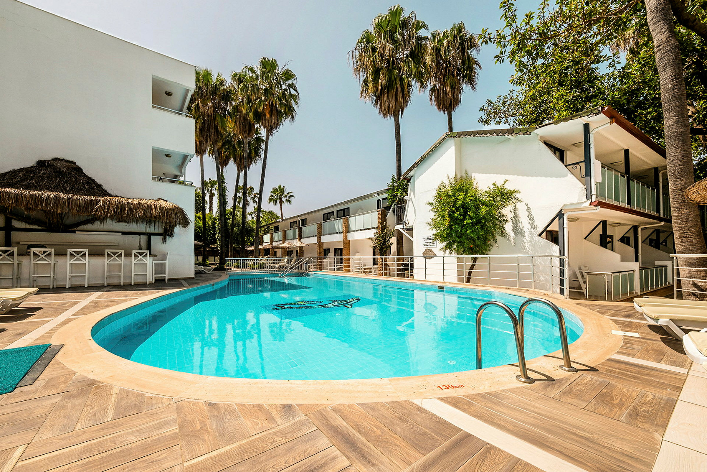 Utomhuspool vid hotell med solstolar och palmer. (AI-genererad text)