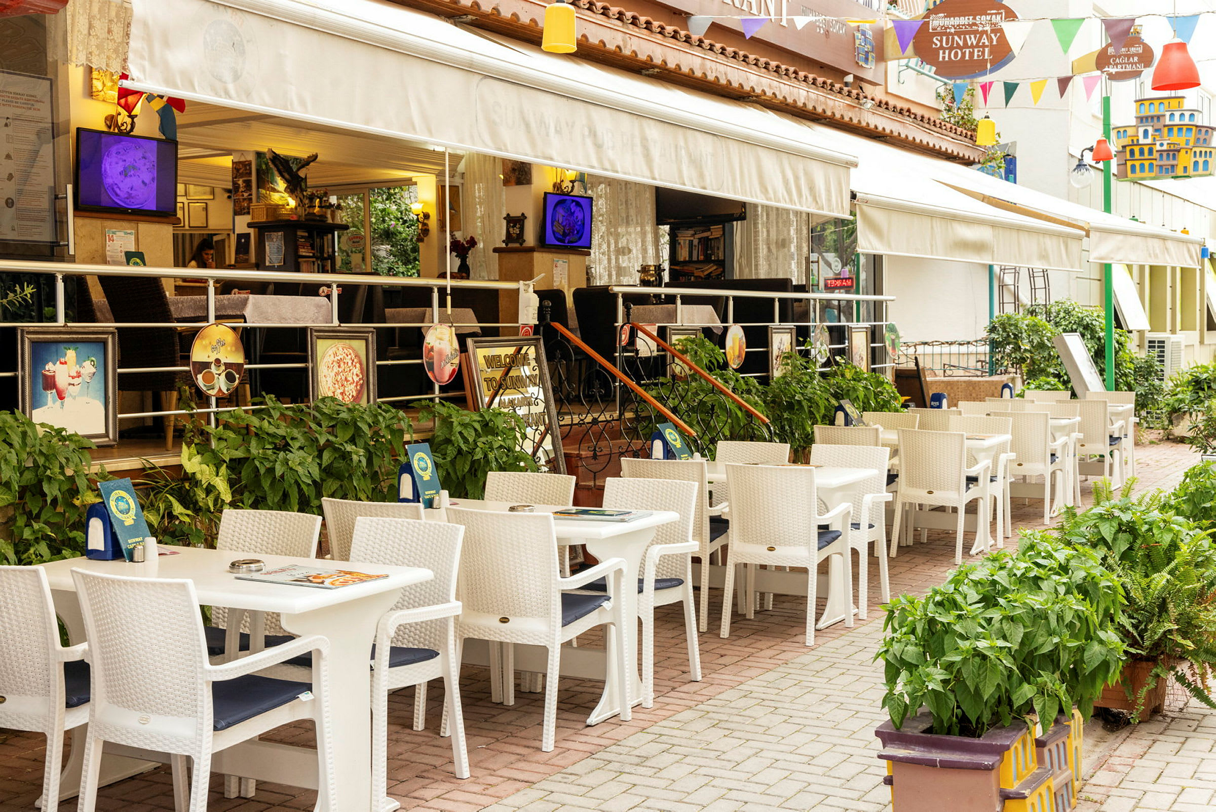 Restaurang med uteservering med vita bord och stolar vid ett hotell. (AI-genererad text)