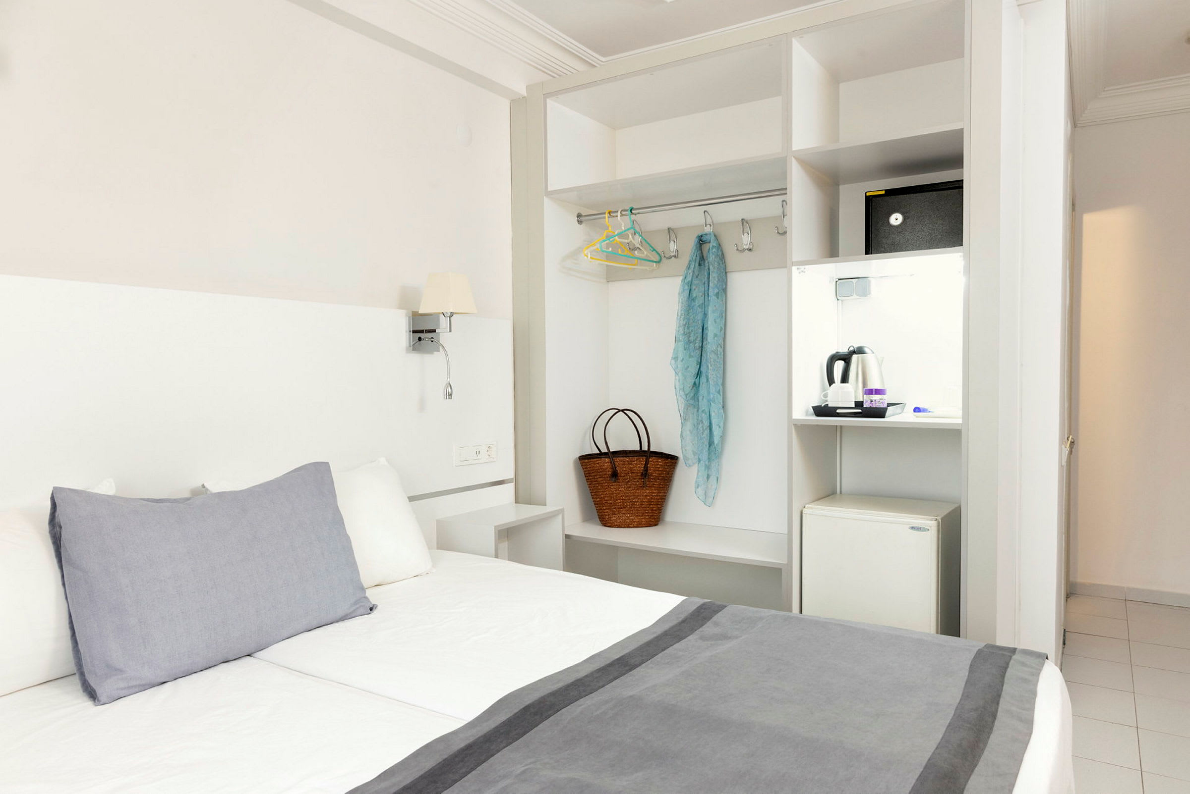 Hotellrum med säng, garderob och en minikyl. (AI-genererad text)