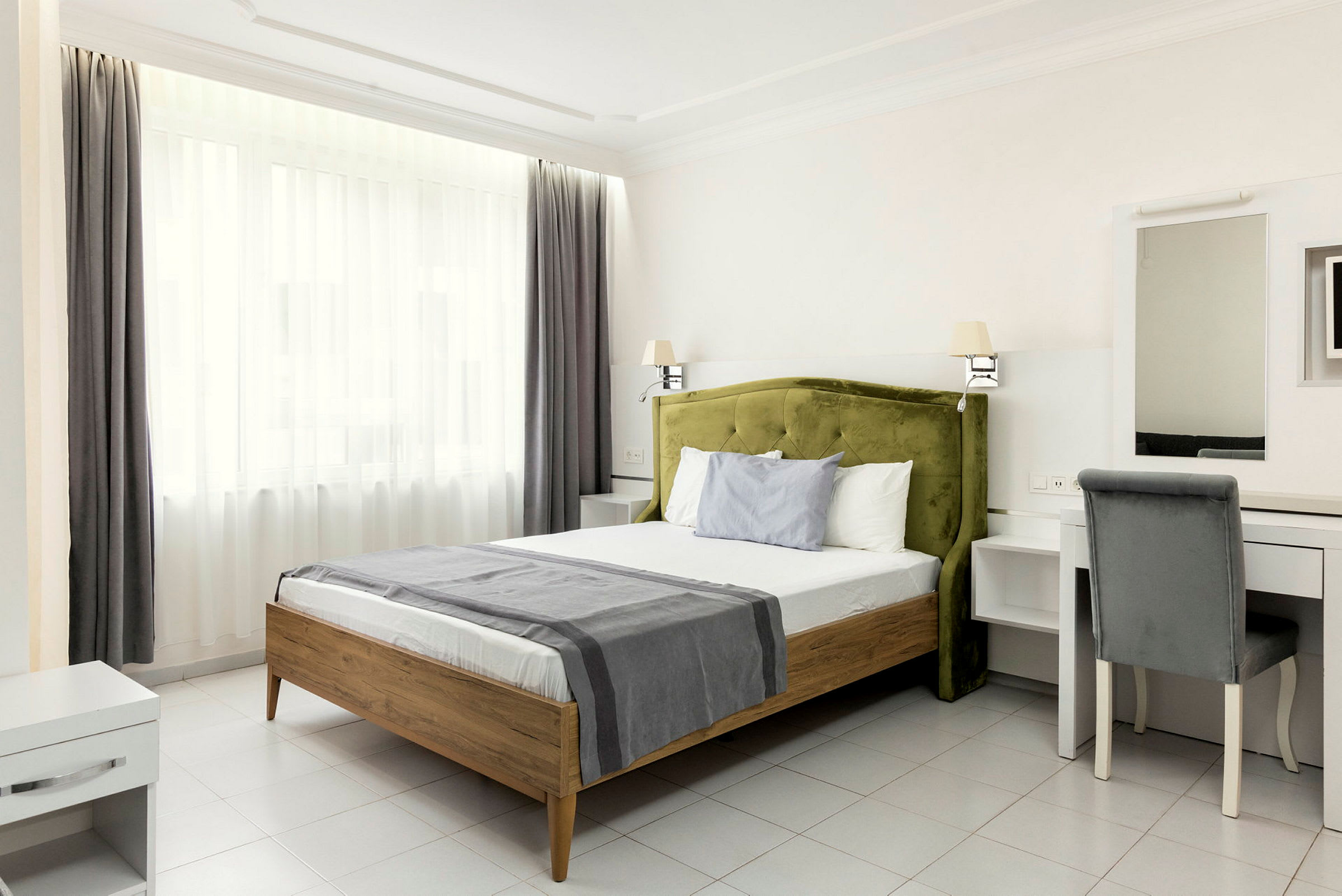 Ett ljust hotellrum med en säng, skrivbord och stol. (AI-genererad text)