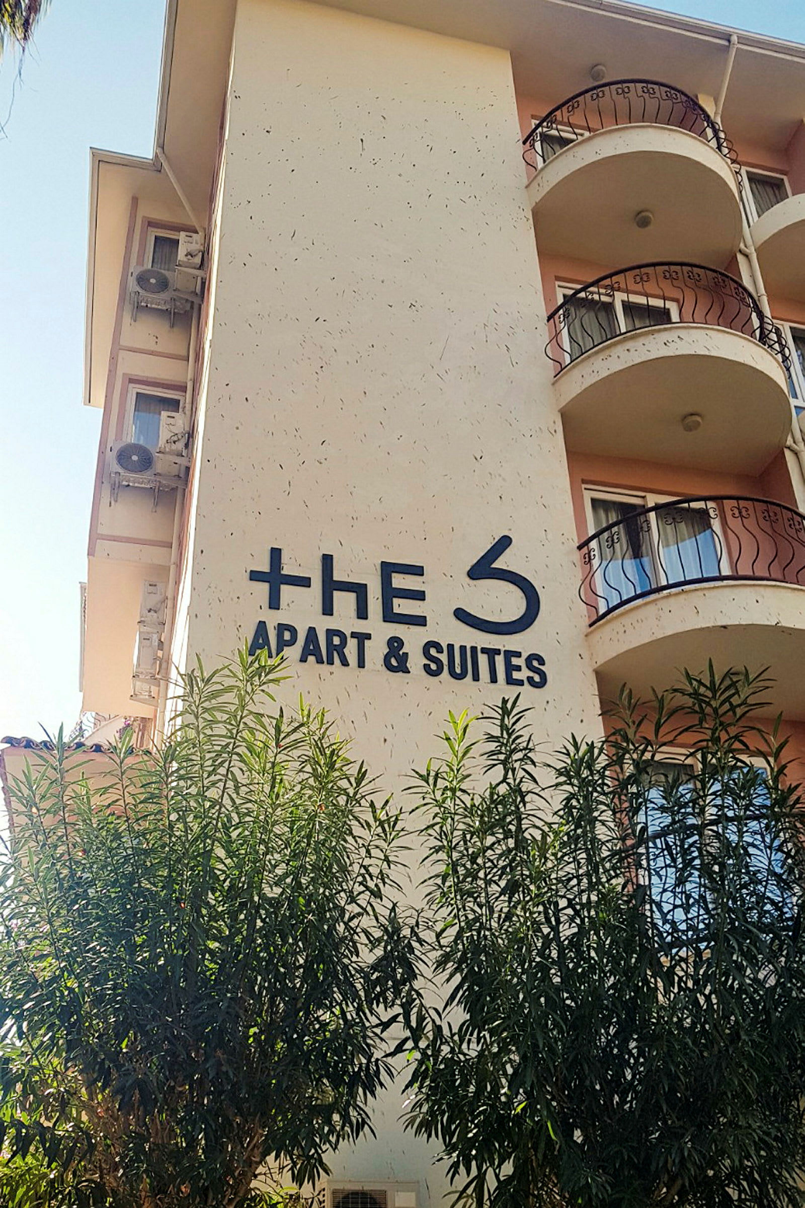 Byggnad med en skylt där det står "The S Apart & Suites", omgiven av träd. (AI-genererad text)