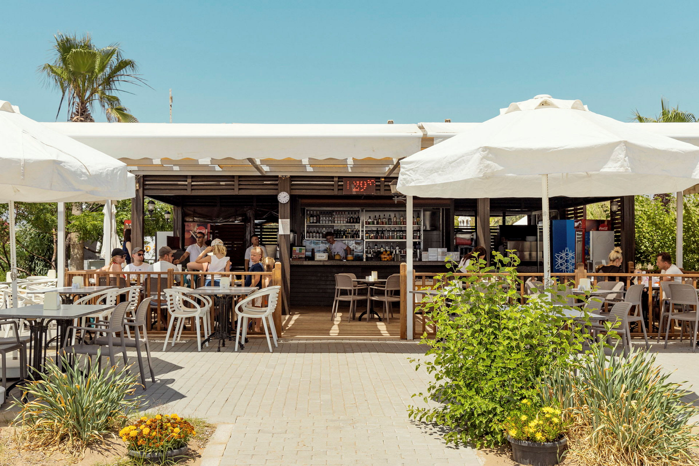 Utomhusrestaurang med parasoller och sittgrupper på terrass. (AI-genererad text)