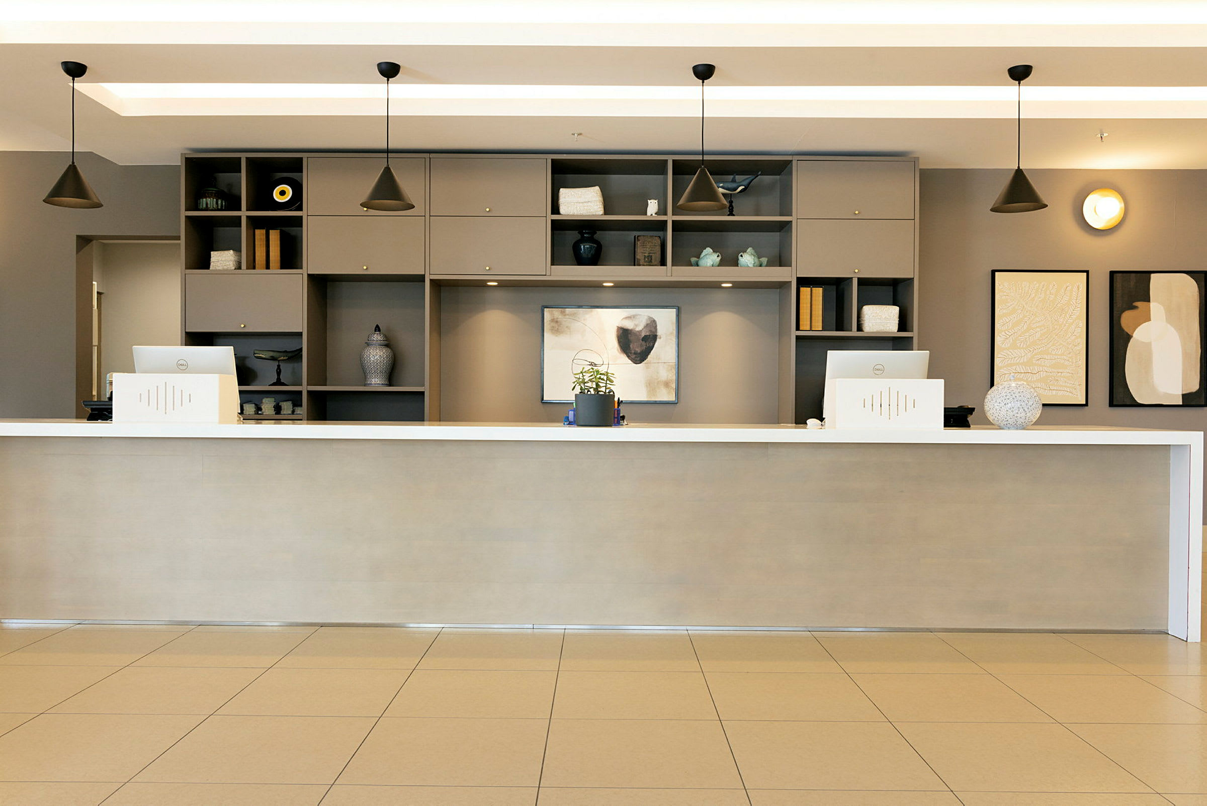 Hotellreception med en lång disk, två datorer och dekorativa hyllor bakom. (AI-genererad text)