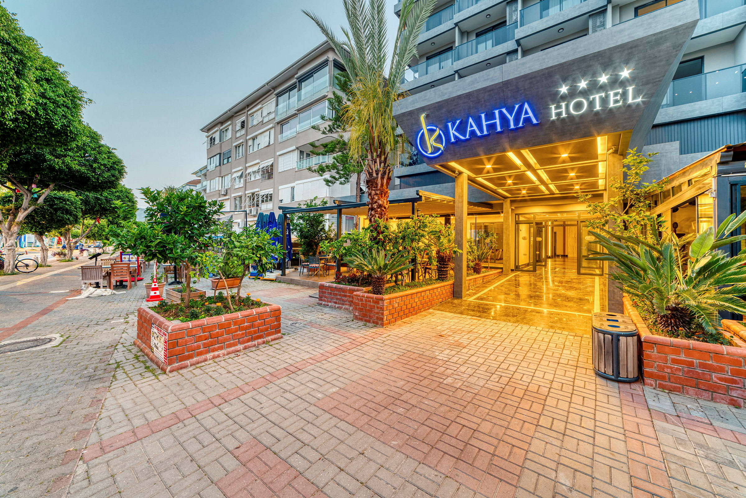 Entrén till Kahya Hotel med omgivande grönskande planteringar och moderna byggnader i bakgrunden. (AI-genererad text)