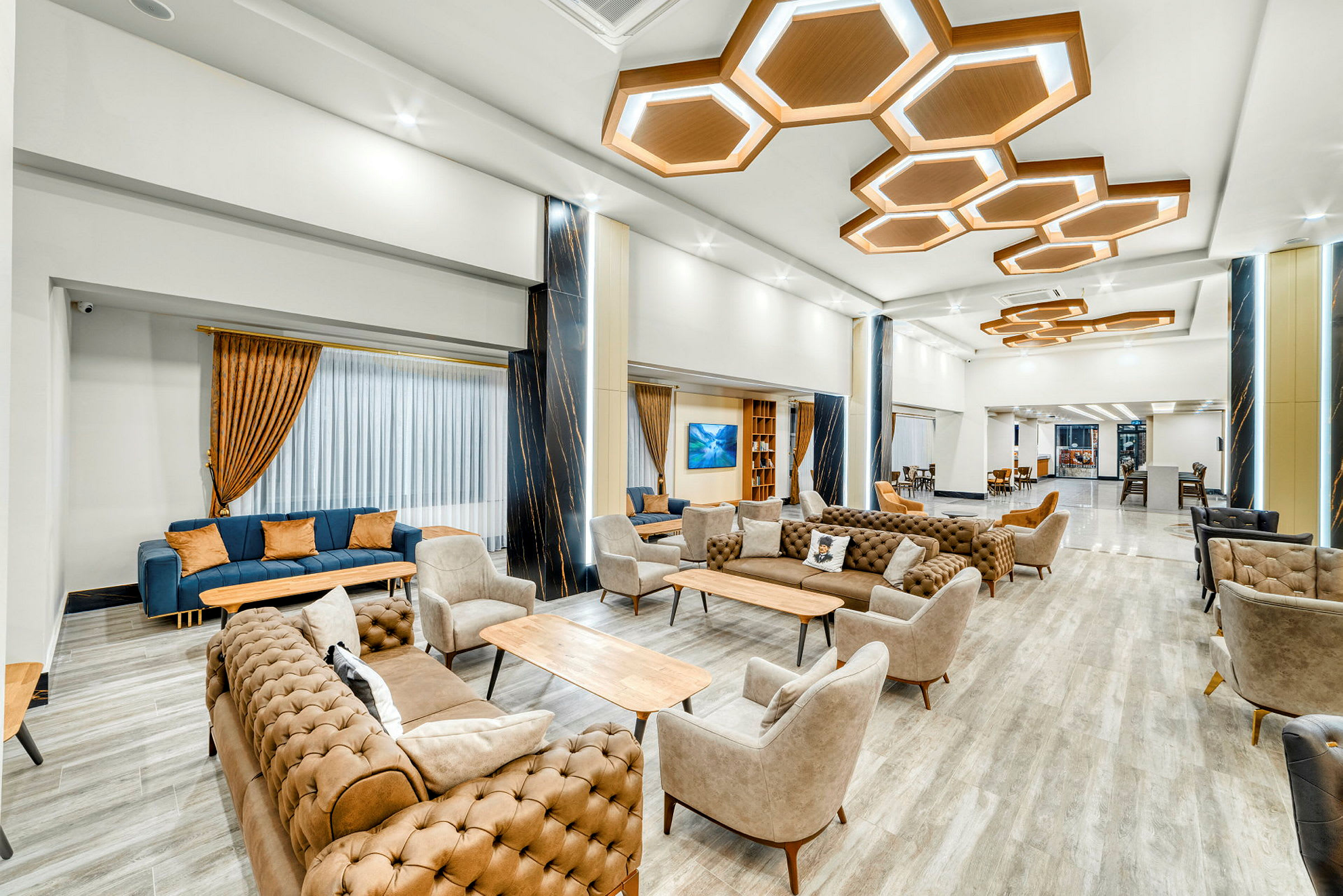En modern loungemiljö med sittgrupper i neutrala färger och upplysta geometriska takdetaljer. (AI-genererad text)