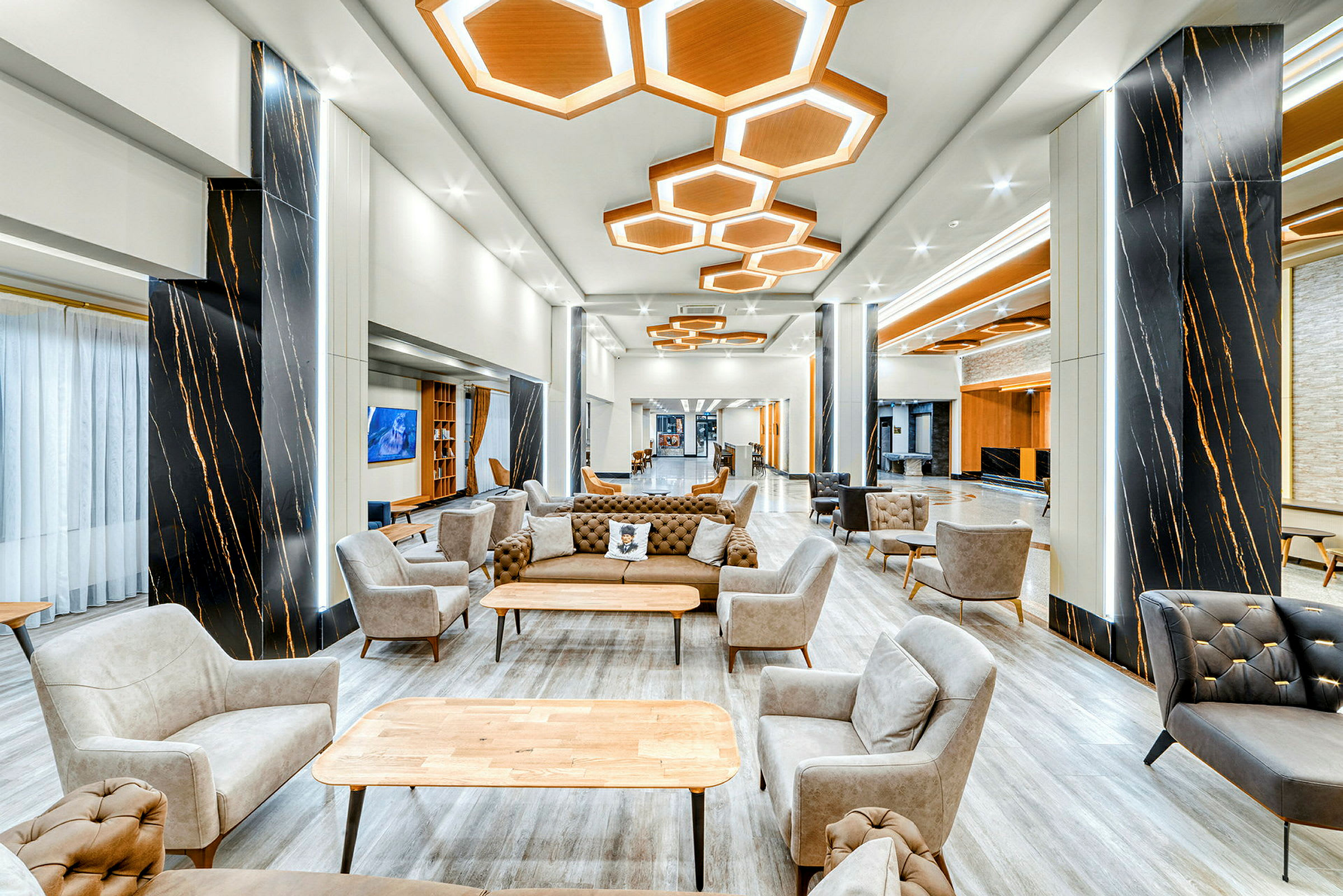 En modern och välbelyst lounge med stolar och soffor framför ett bord. (AI-genererad text)