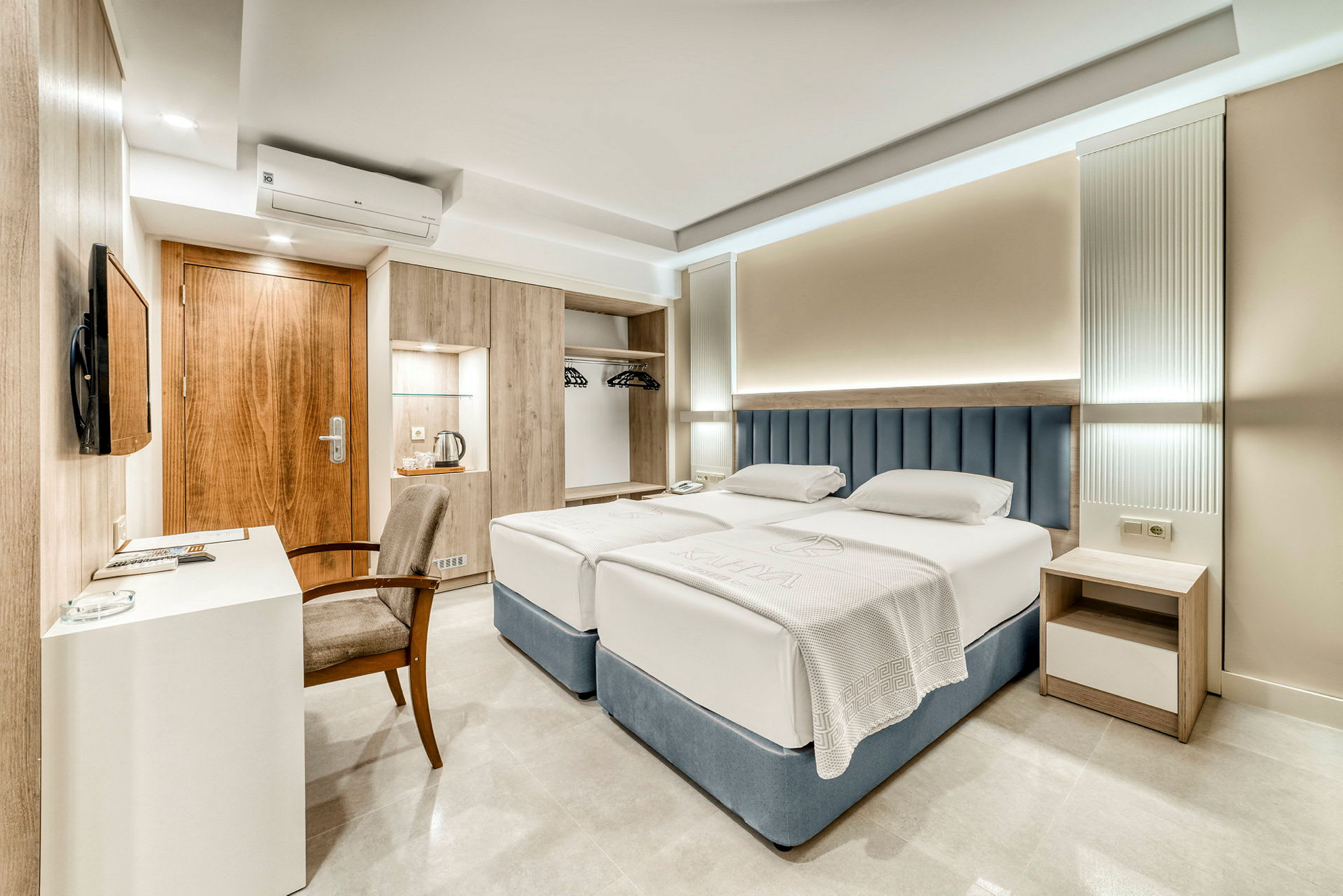 Ett hotellrum med två enkelsängar, skrivbord, stol och garderob. (AI-genererad text)