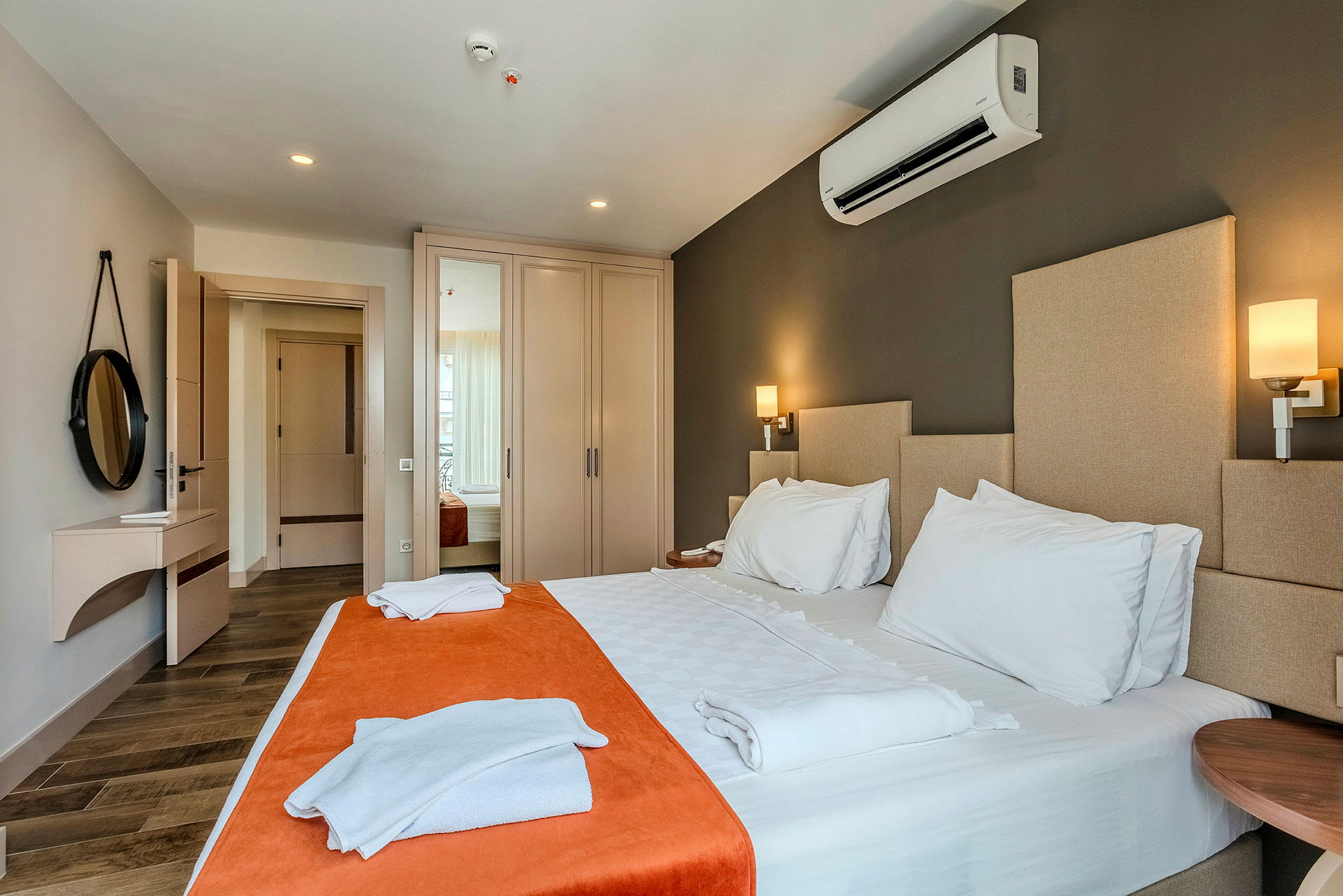 Ett hotellrum med dubbelsäng, sänglampor och garderober. (AI-genererad text)