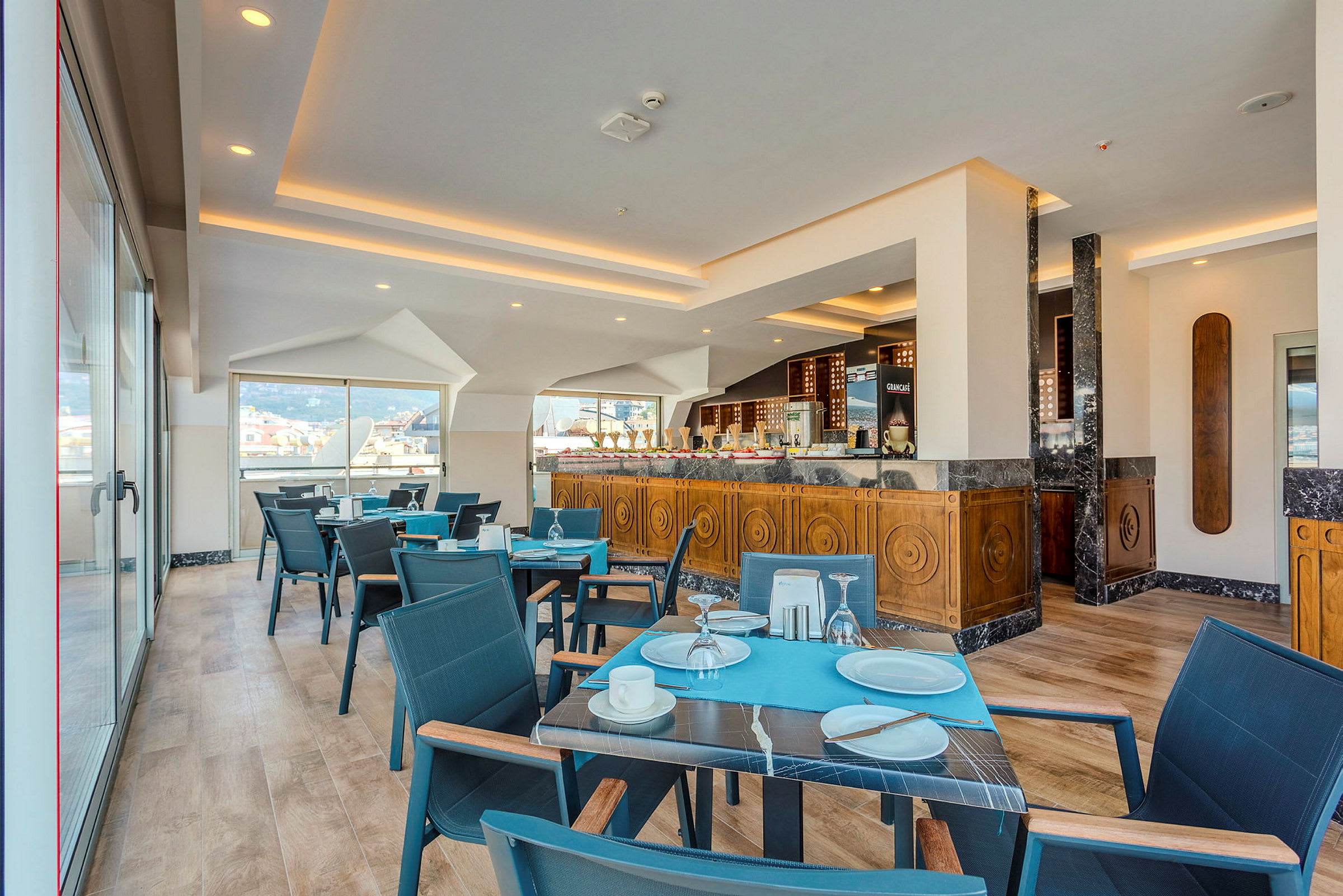 Restaurang med matbord och stolar, samt serveringsområde med trädesign. (AI-genererad text)
