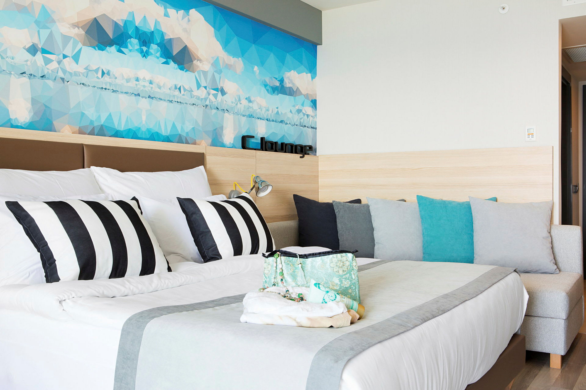 En modern hotellrum med en säng, färgade kuddar och en dekorativ bakgrund. (AI-genererad text)
