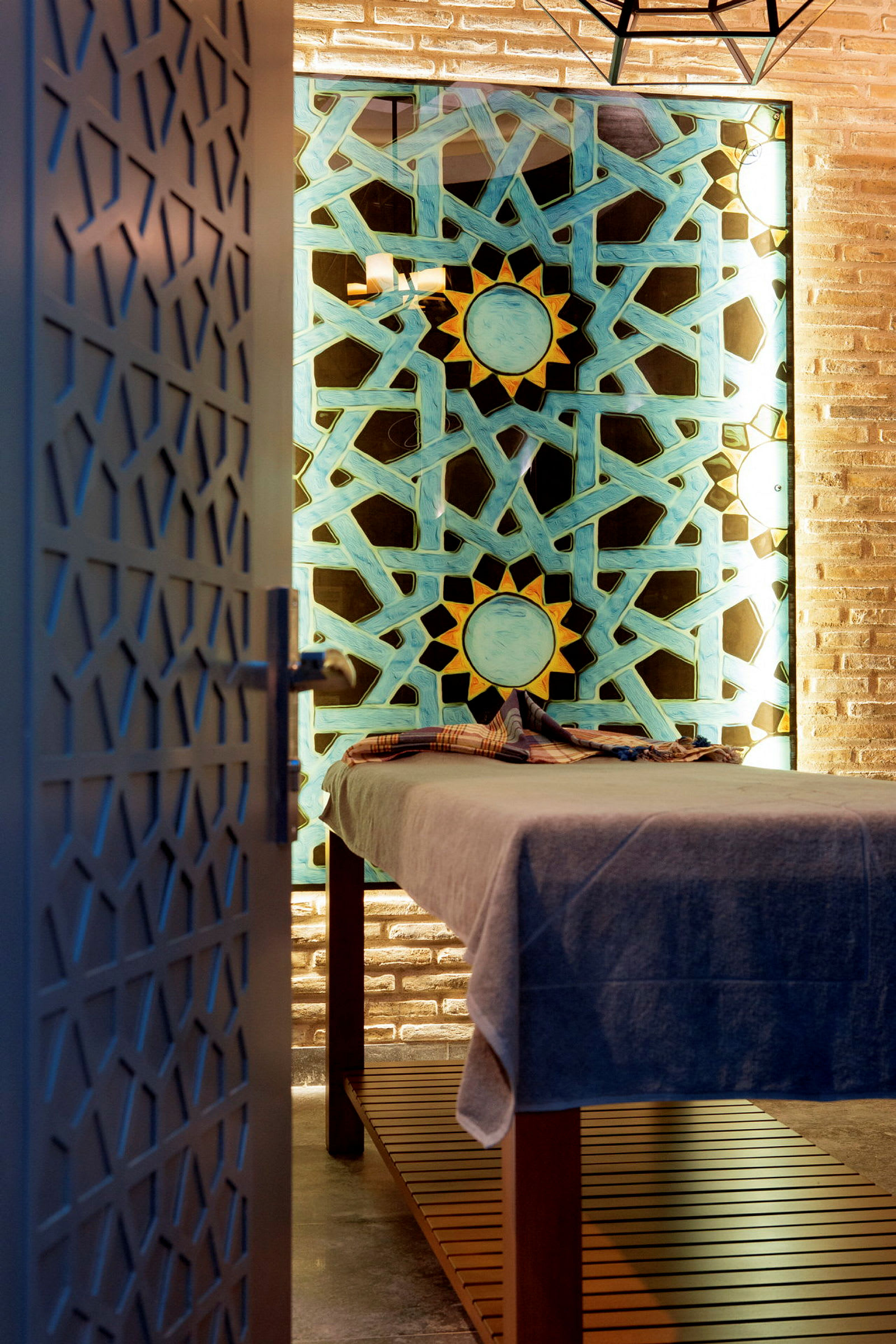 Spa-rum med massagebänk, dekorerad vägg i blått och gult mönster. (AI-genererad text)