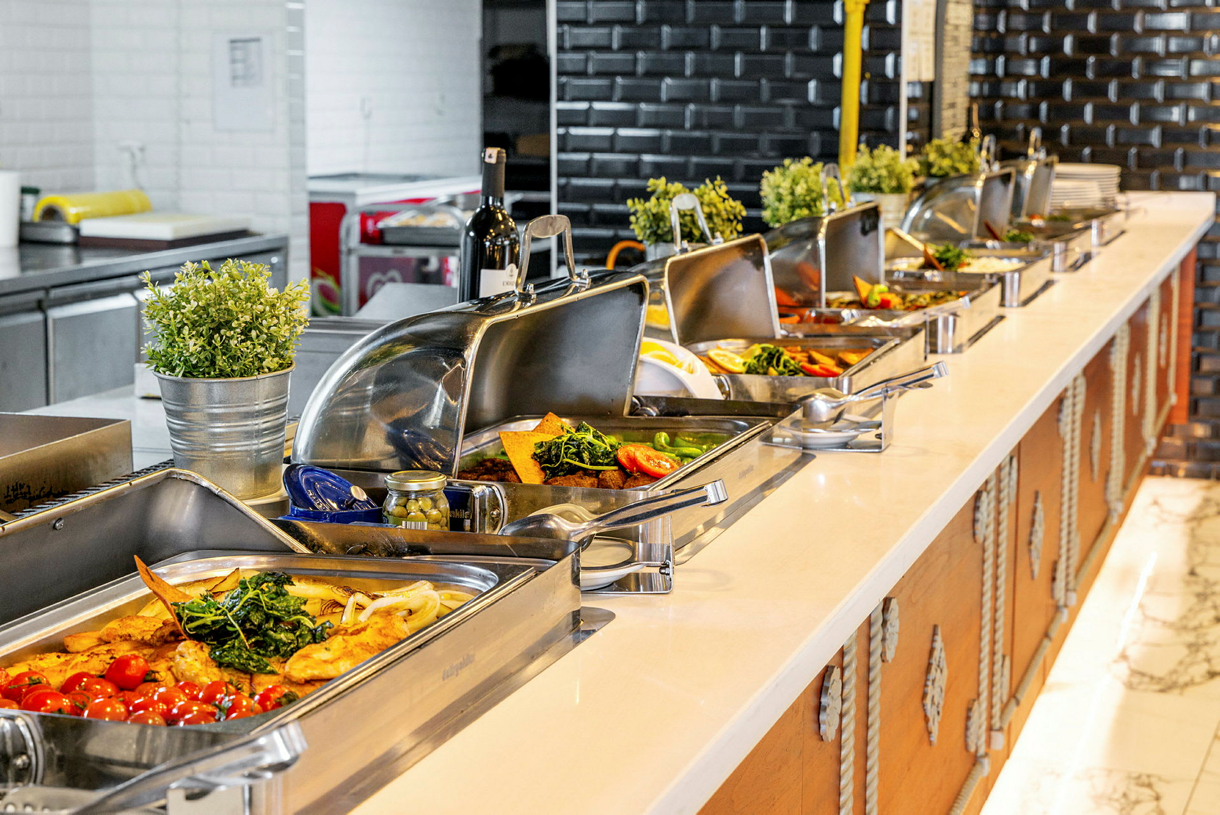Buffébord med olika rätter serverade i rostfria behållare. (AI-genererad text)