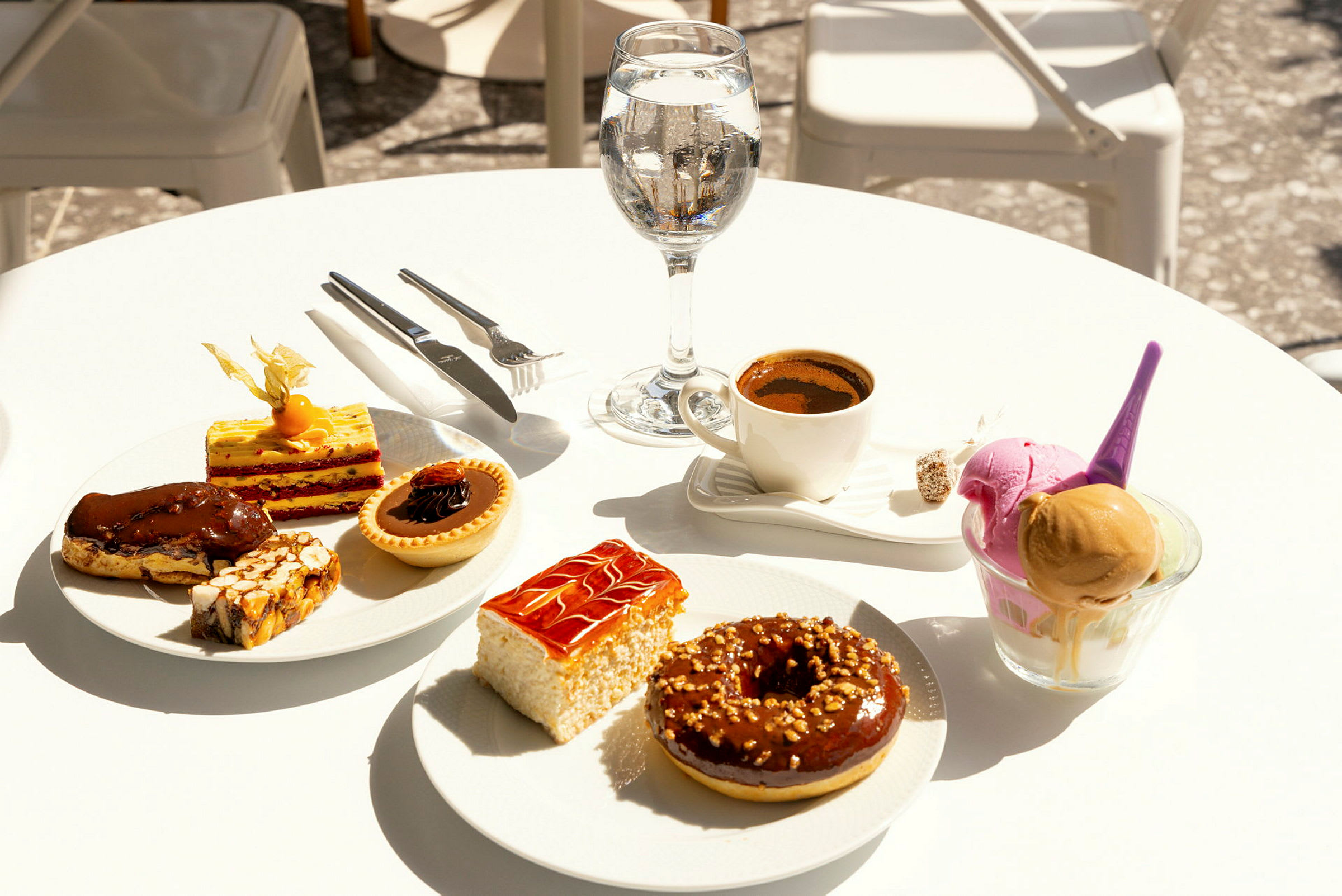 Ett bord med olika sötsaker, kaffe och ett glas vatten. (AI-genererad text)
