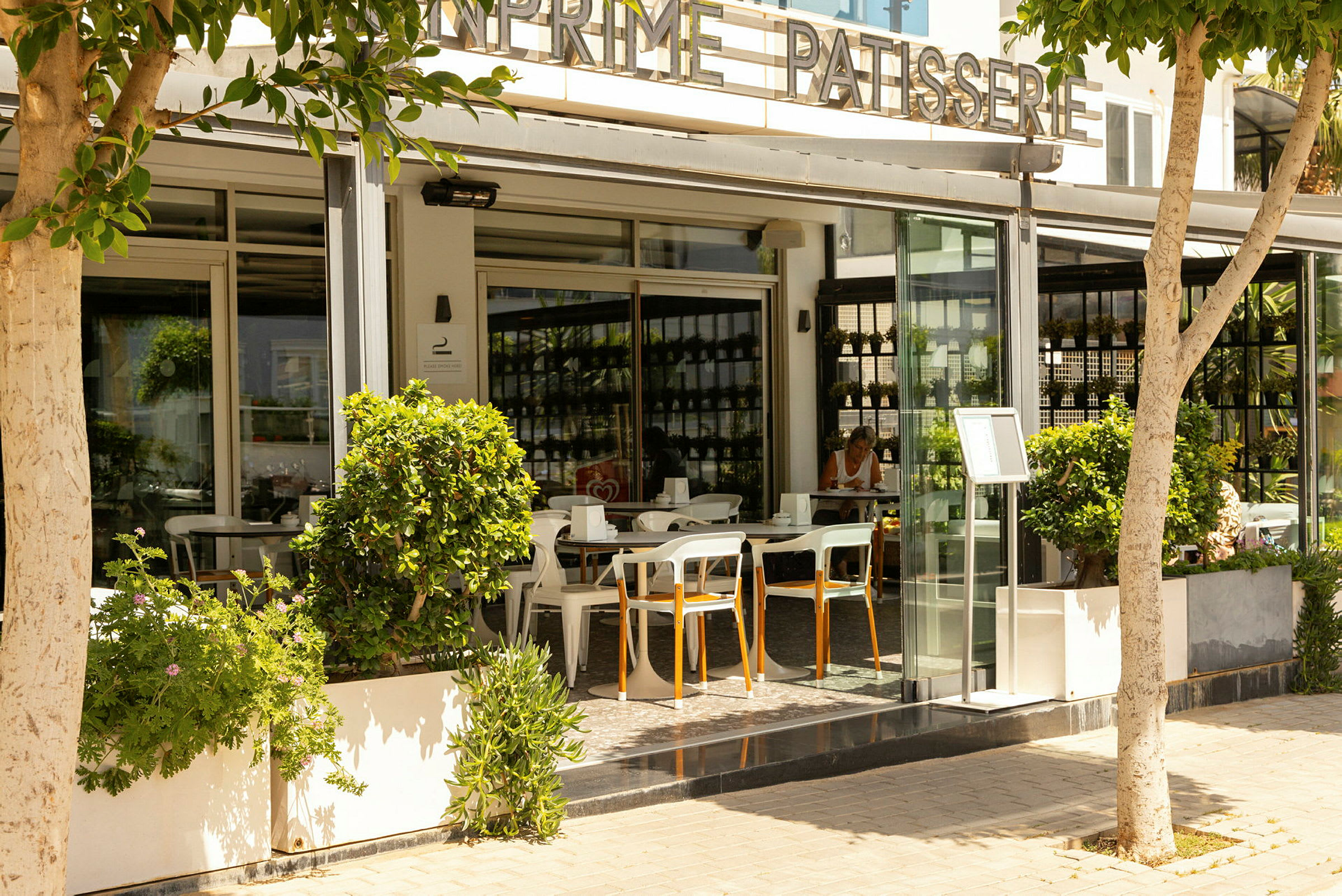 En modern kafé med uteservering omgiven av grönska. (AI-genererad text)