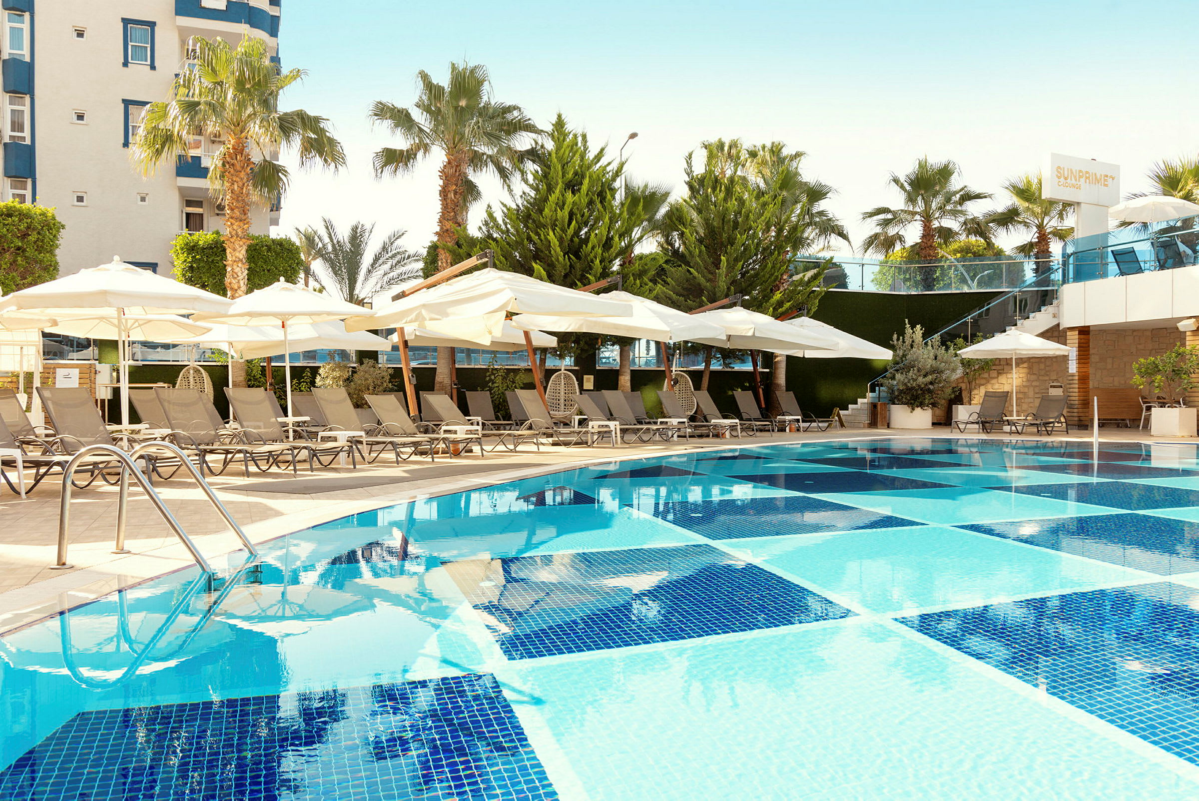Utomhuspool med solstolar och parasoller i ett hotellområde. (AI-genererad text)
