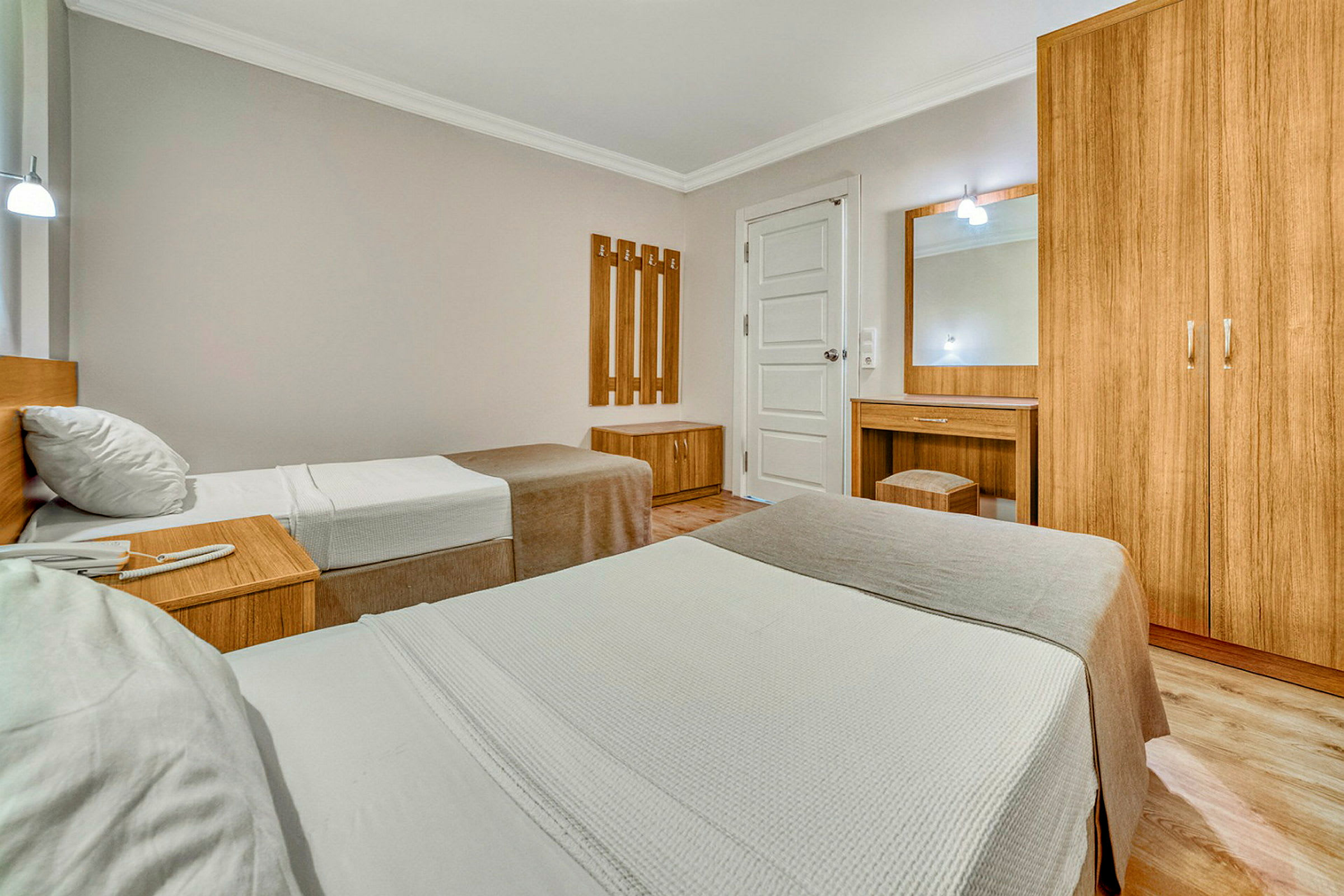 Inredning i ett hotellrum med två enkelsängar, träskåp och sminkbord. (AI-genererad text)