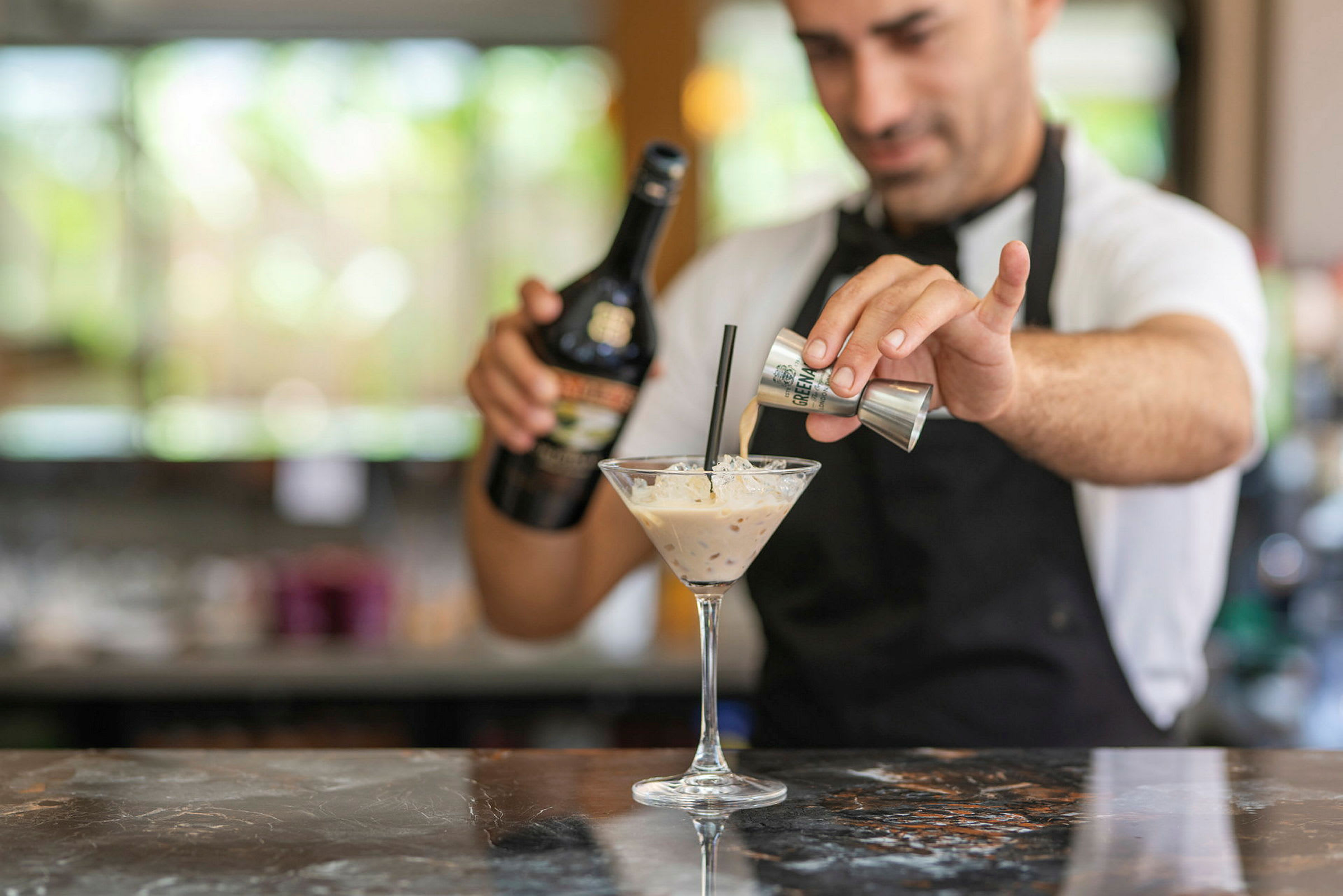 En bartender som tillreder en cocktail med gräddlikör. (AI-genererad text)
