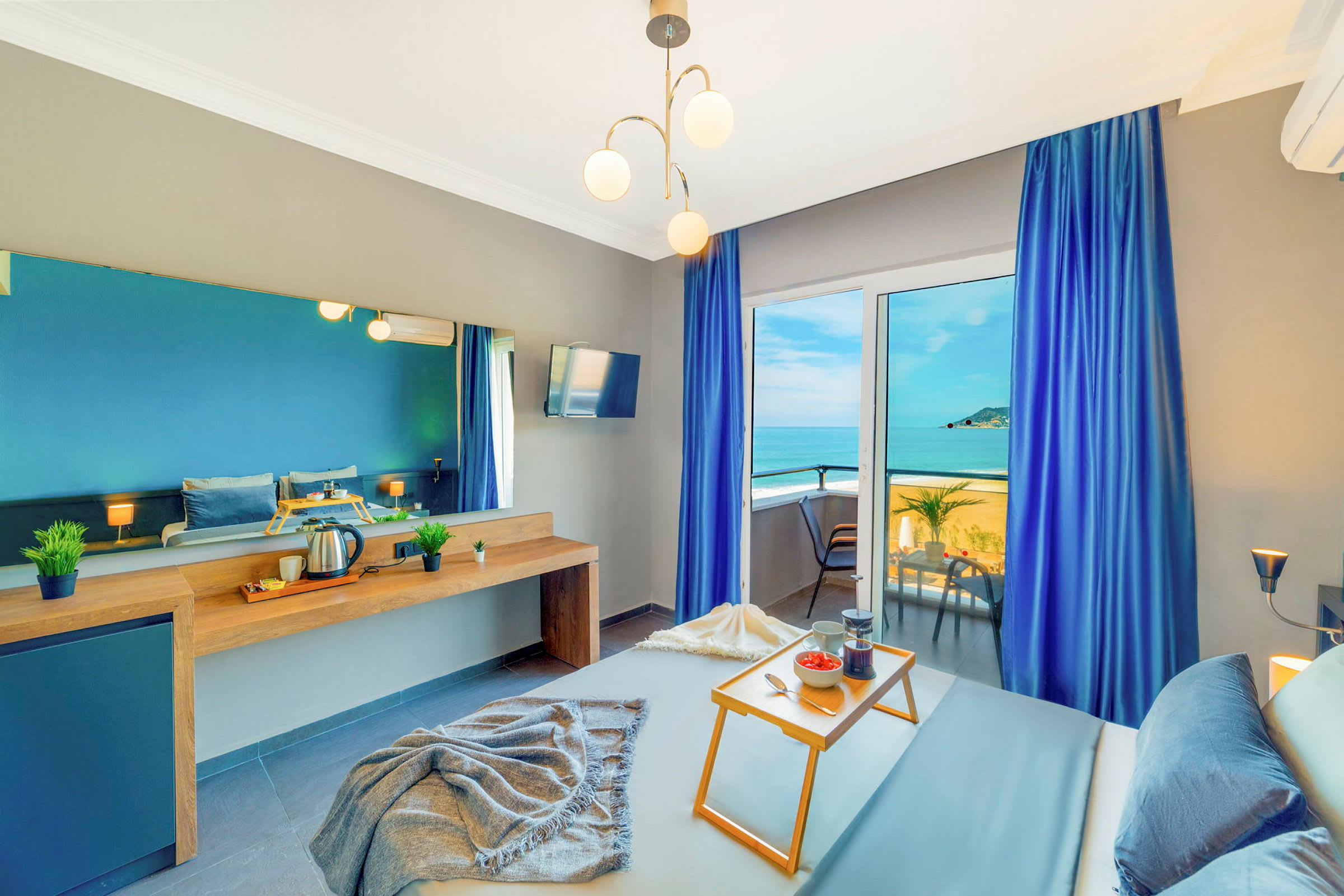 Ett hotellrum med havsutsikt, blå gardiner och frukostbricka på sängen. (AI-genererad text)