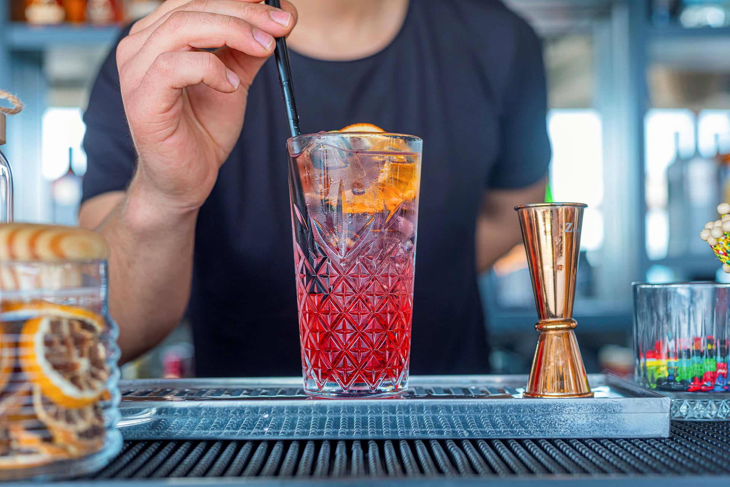 En drink med is och ett sugrör hålls vid en bar. (AI-genererad text)