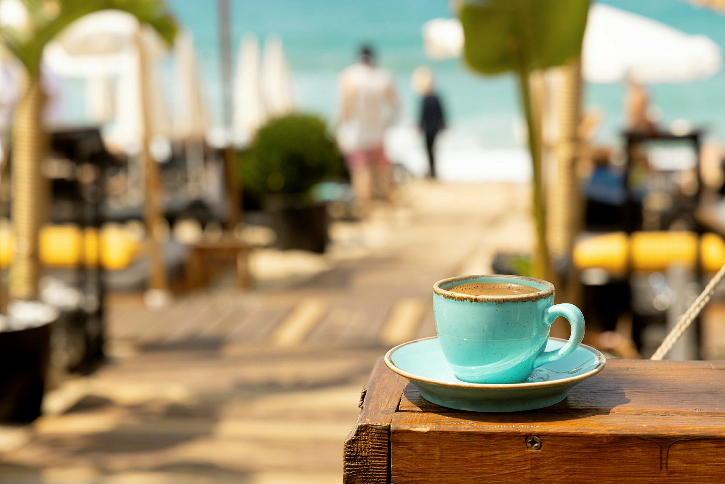 En kopp kaffe på en träyta med en strand i bakgrunden. (AI-genererad text)