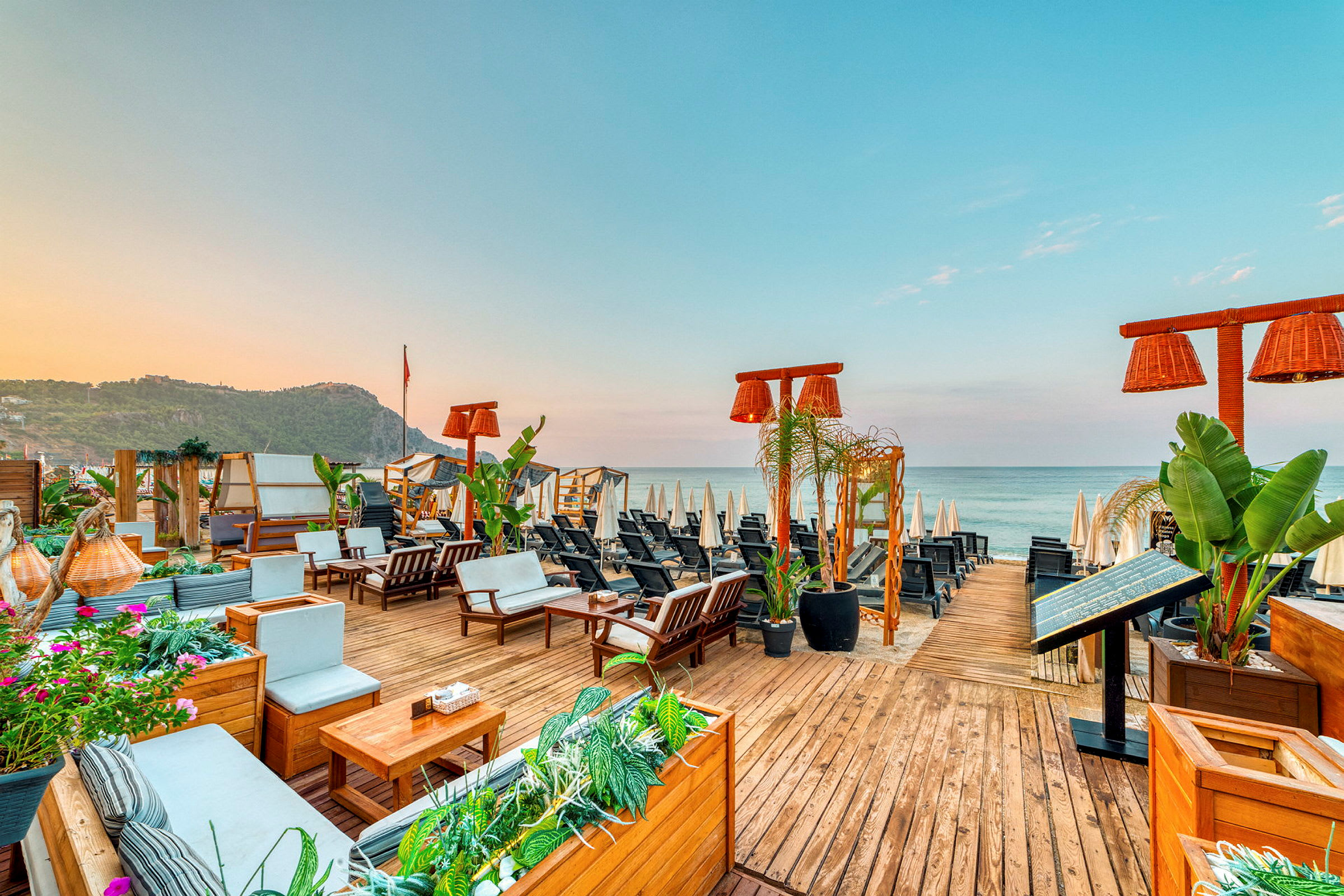 Utsikt över en strandbar med utemöbler och parasoller vid havet. (AI-genererad text)
