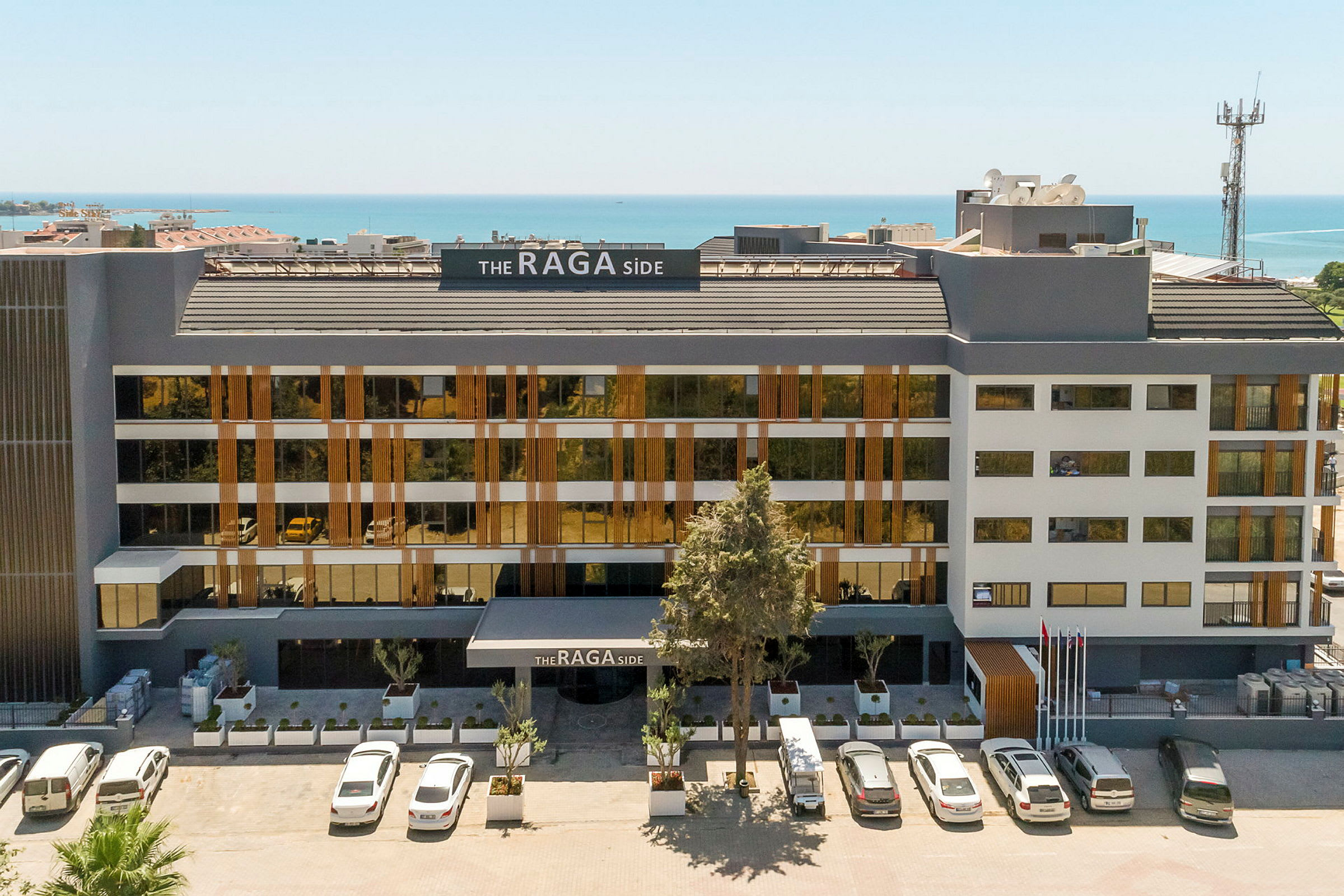 Framsidan av ett hotell med parkering och havsutsikt. (AI-genererad text)
