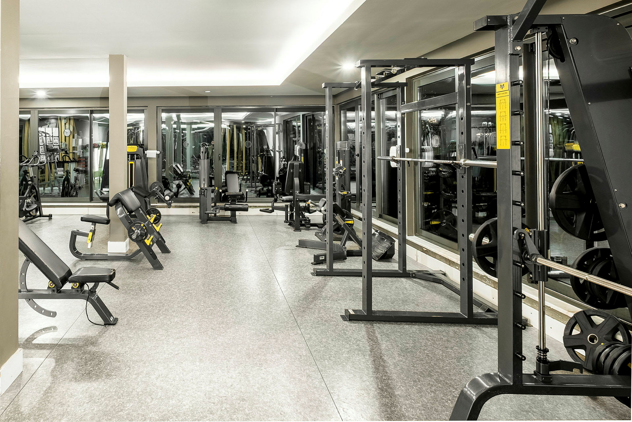 Ett välutrustat gym med olika träningsmaskiner och speglar längs väggarna. (AI-genererad text)