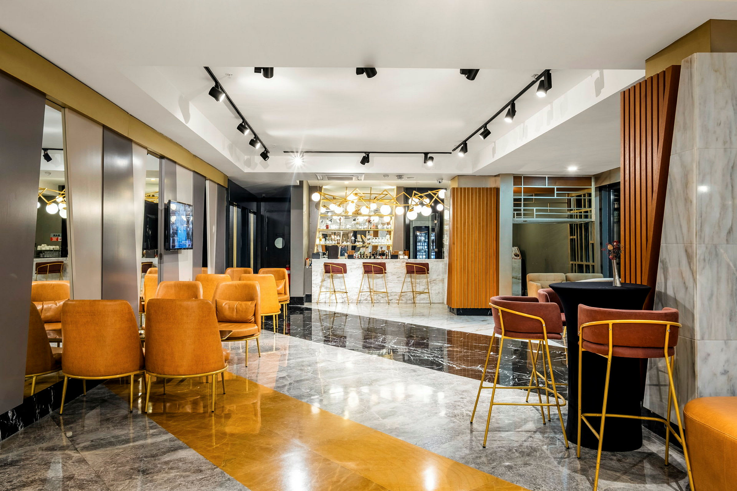 Interiören visar en modern lounge med sittplatser, soffor och en bar i bakgrunden som är detaljerad med ljuskronor och speglar. (AI-genererad text)