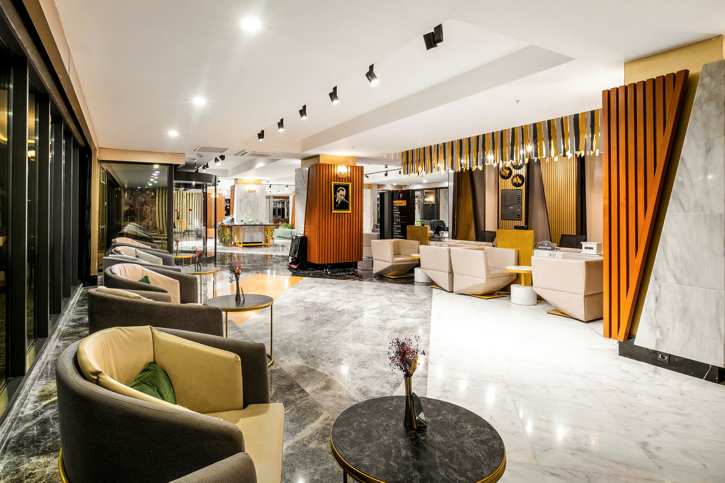 Ett modernt hotellobbyområde med sittgrupper, soffor och bord i en stilren miljö med ljusa färger och trämaterial. (AI-genererad text)
