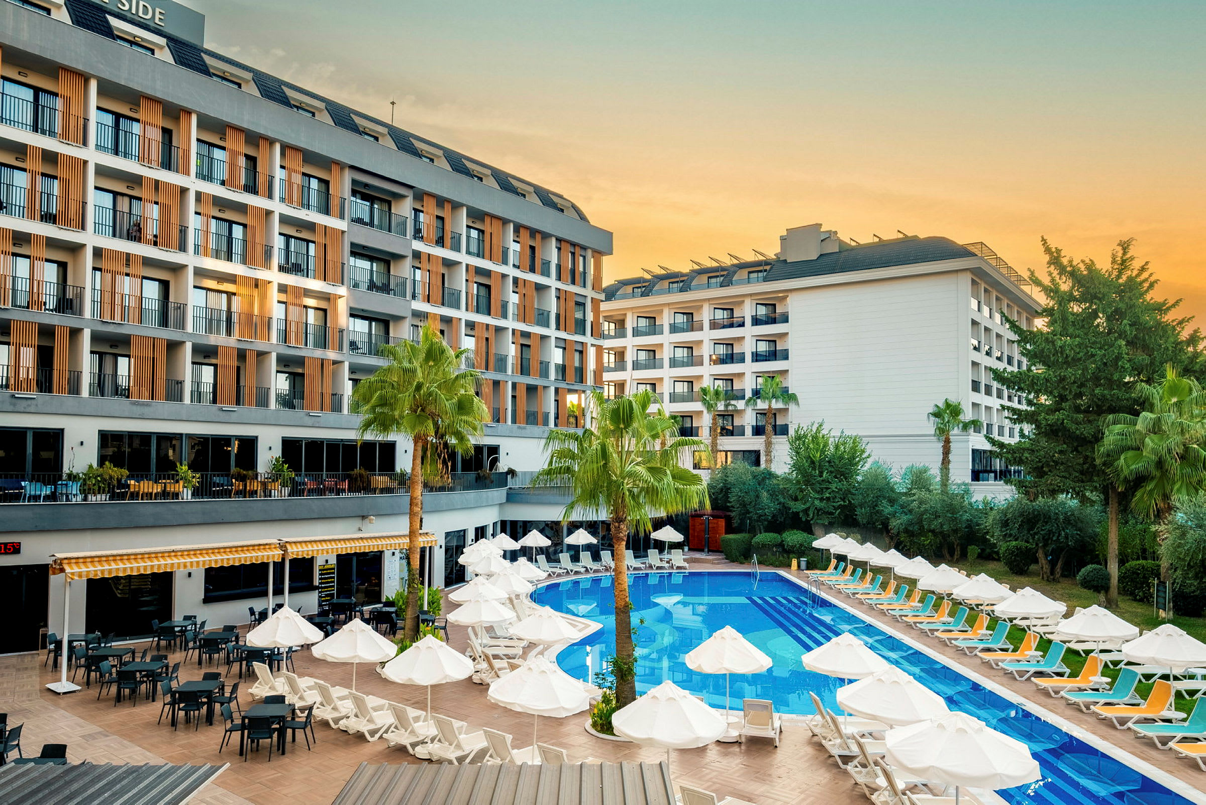 Hotellbyggnad med poolområde, solstolar och parasoller. (AI-genererad text)