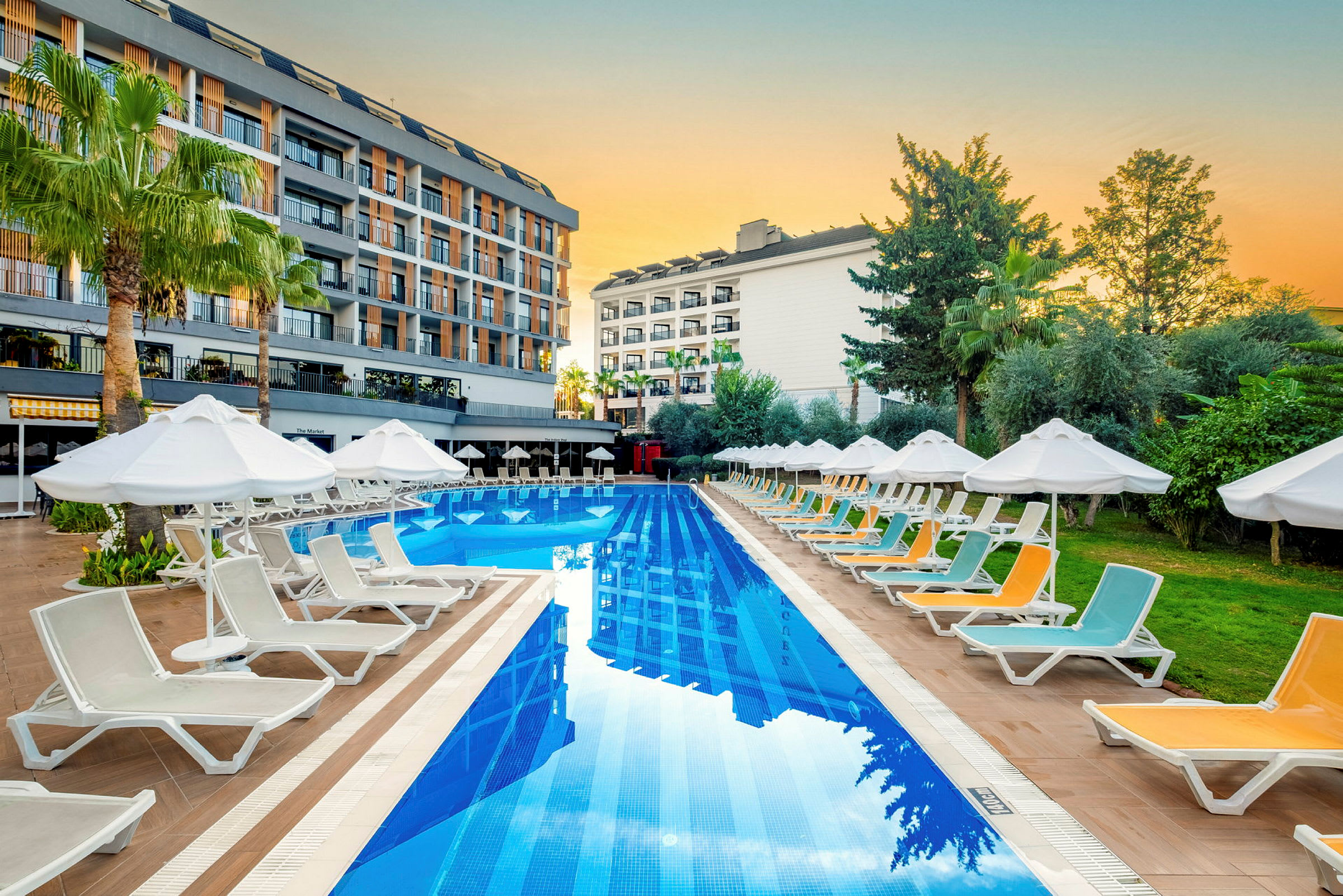 En pool vid ett hotellområde omgiven av solstolar och parasoller. (AI-genererad text)