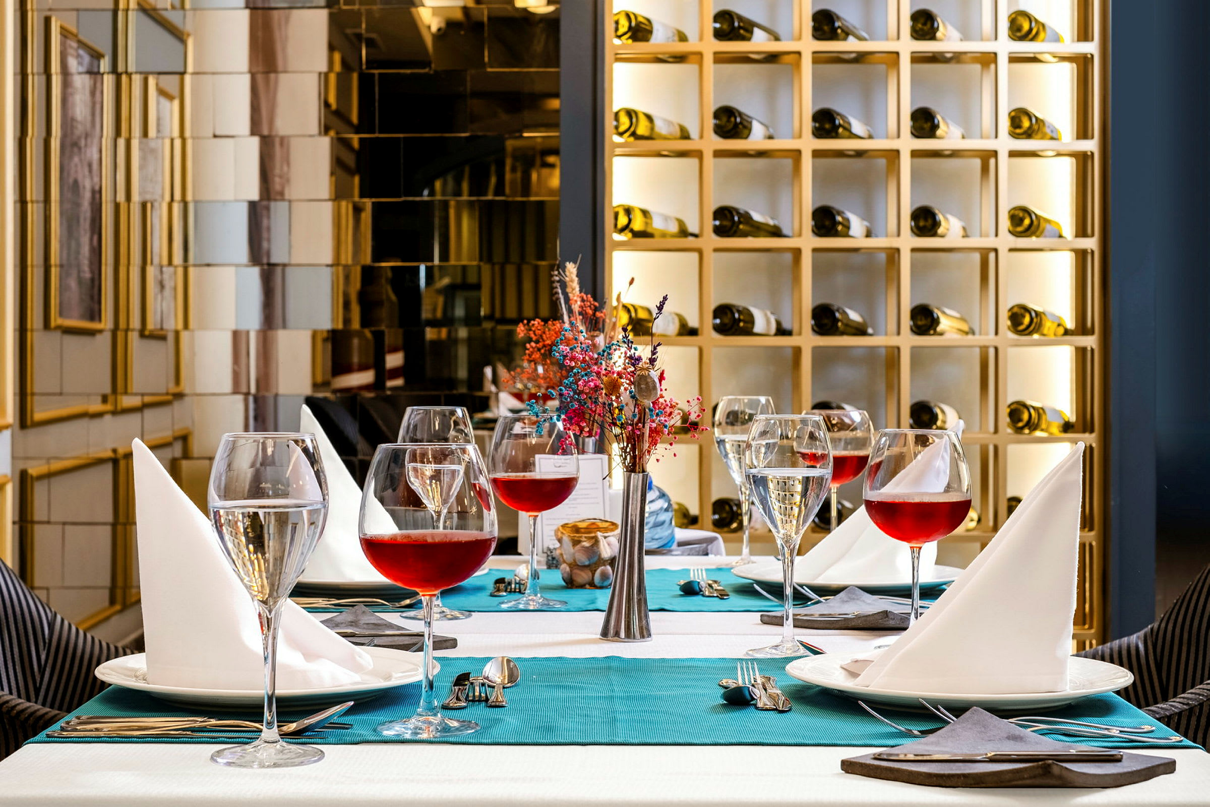Ett elegant dukat bord med vinglas, servetter och en dekoration i en fin restaurangmiljö. (AI-genererad text)